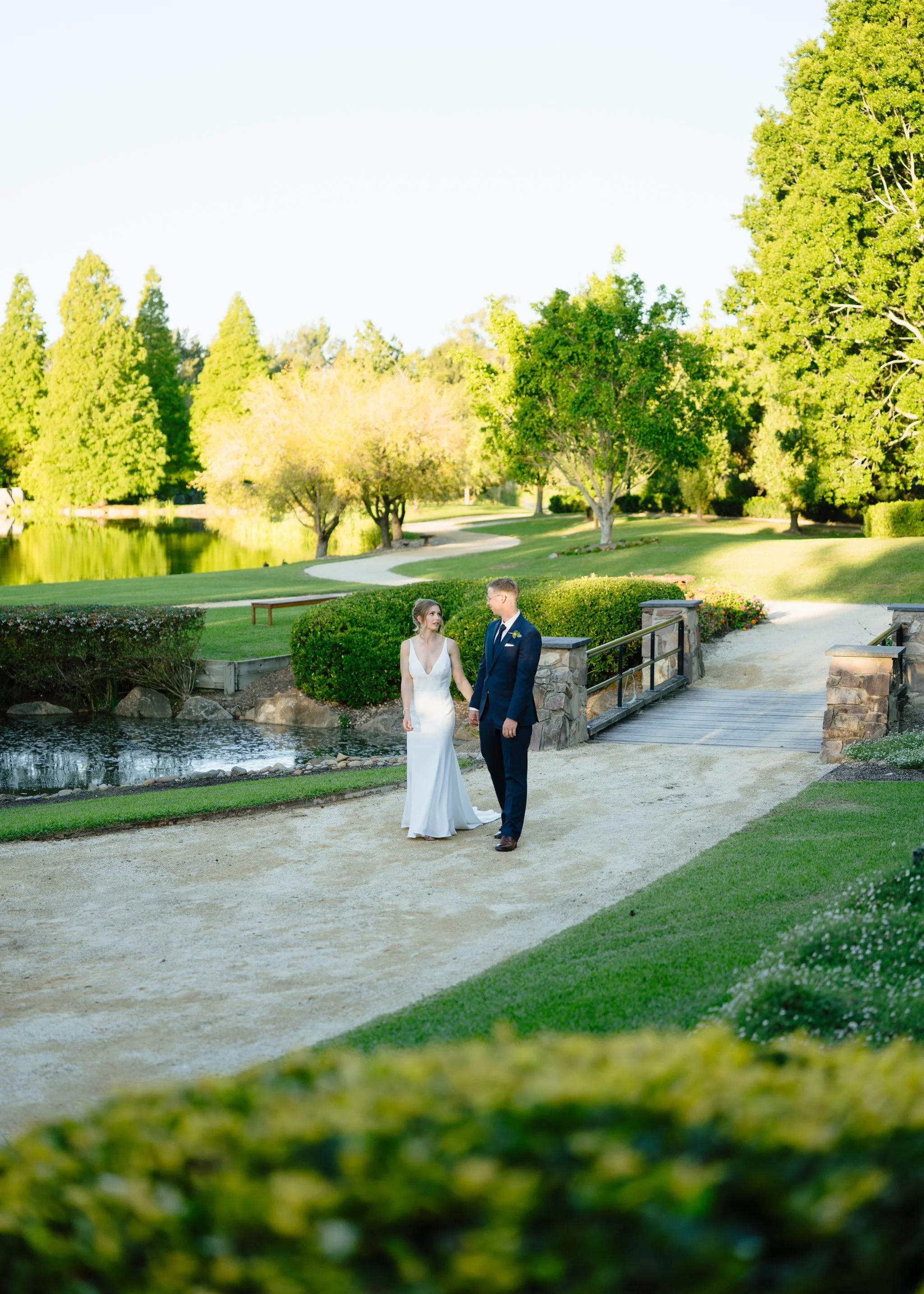 Couple walking lakeside Hunter Valley Gardens wedding