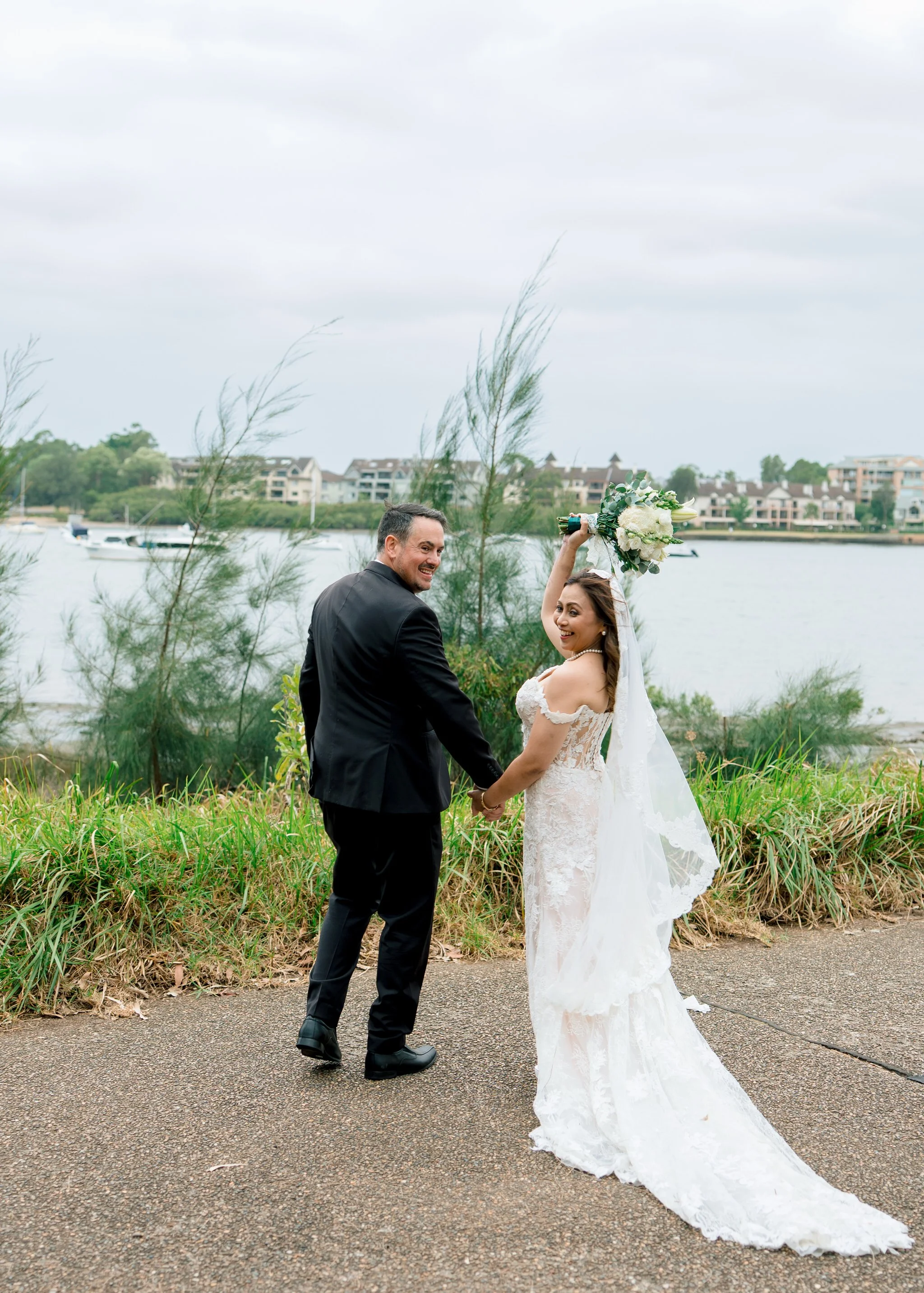 Bride and groom holding hands by waterfront