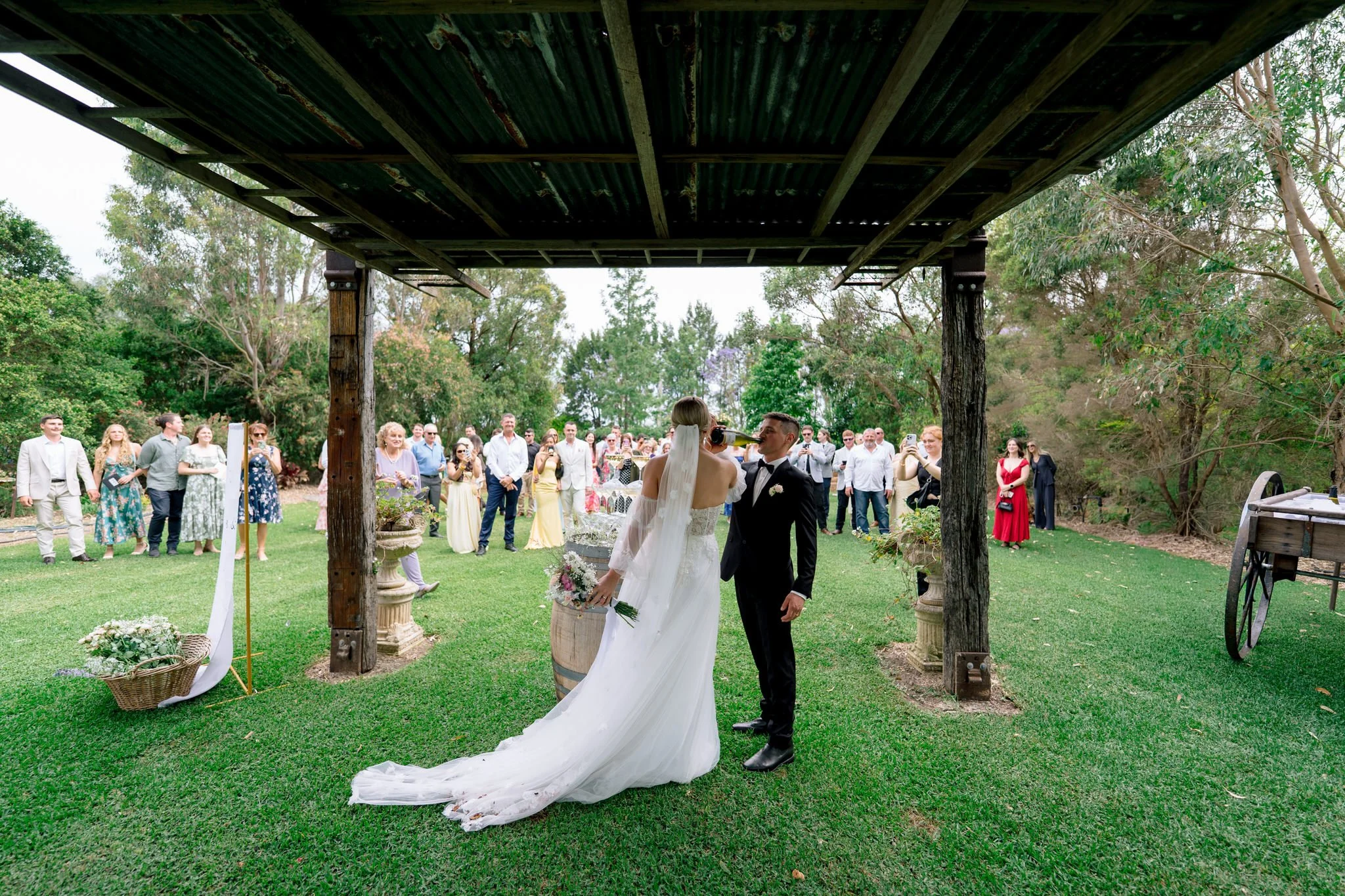 Bride and groom sharing a toast after outdoor wedding ceremony at The Bolwarra Farm NSW with guests watching