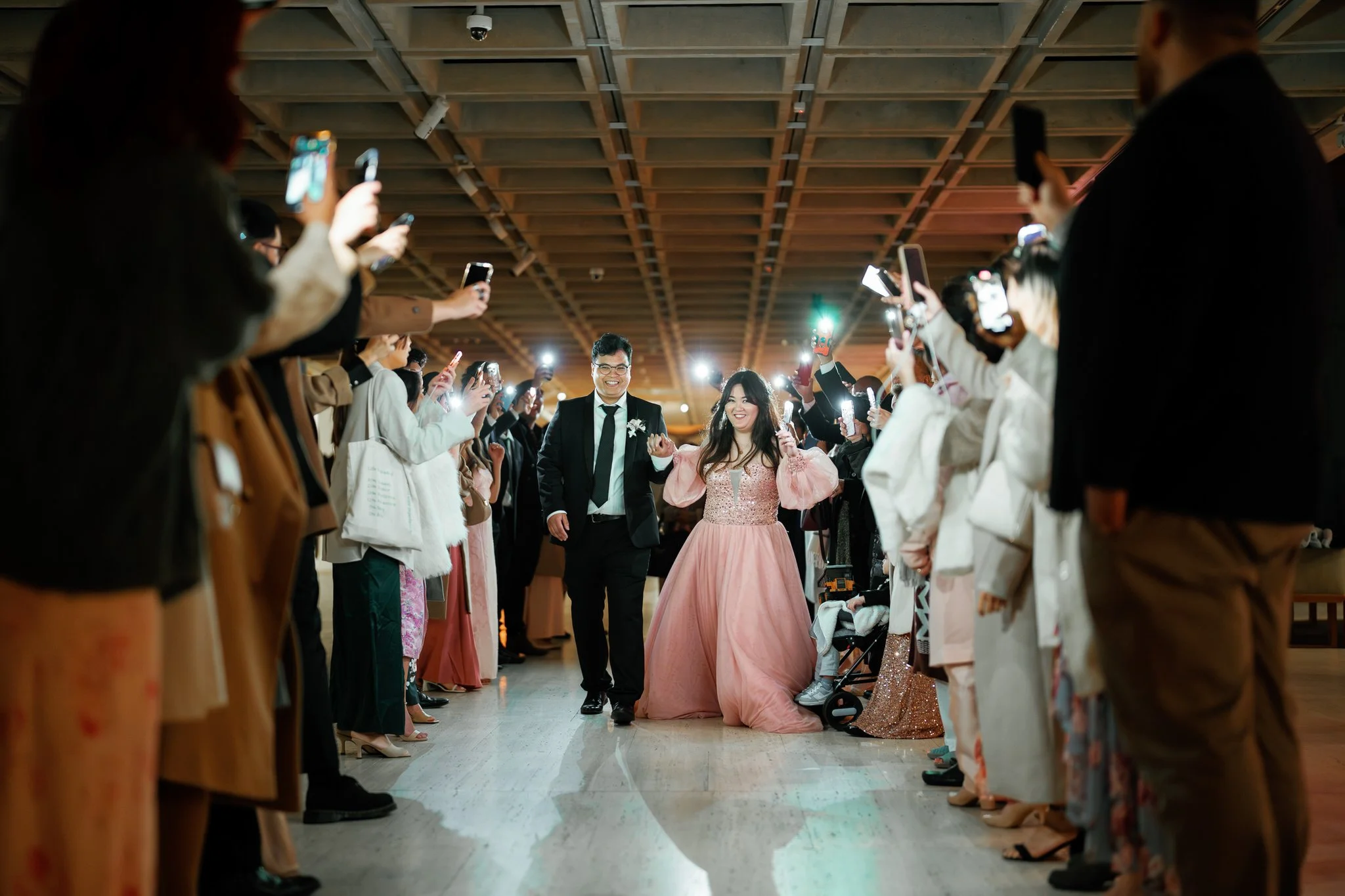 Bride and groom making grand entrance at Art Gallery of NSW wedding, Sydney, with guests capturing the moment on phones