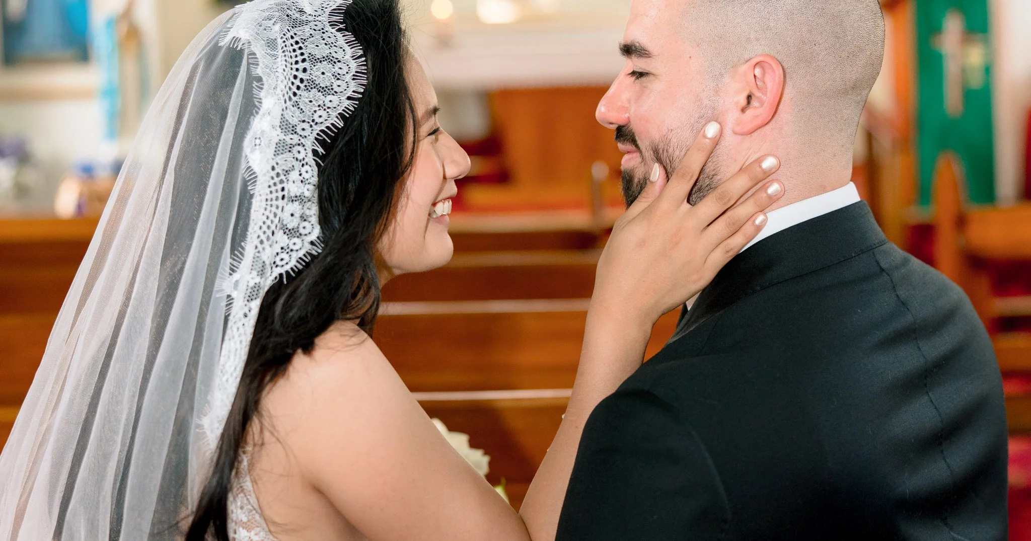 Bride smiling while holding the groom’s face.