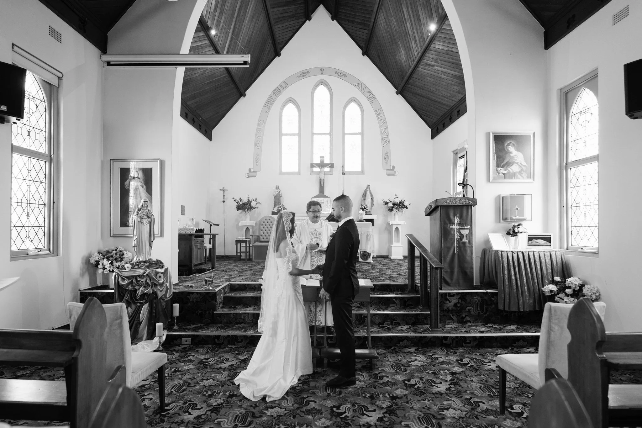 Paolo and Ellie exchange vows before the priest at St Cecilia’s Church in Wyong. A simple, heartfelt ceremony surrounded by family and close friends during their two-hour wedding coverage.