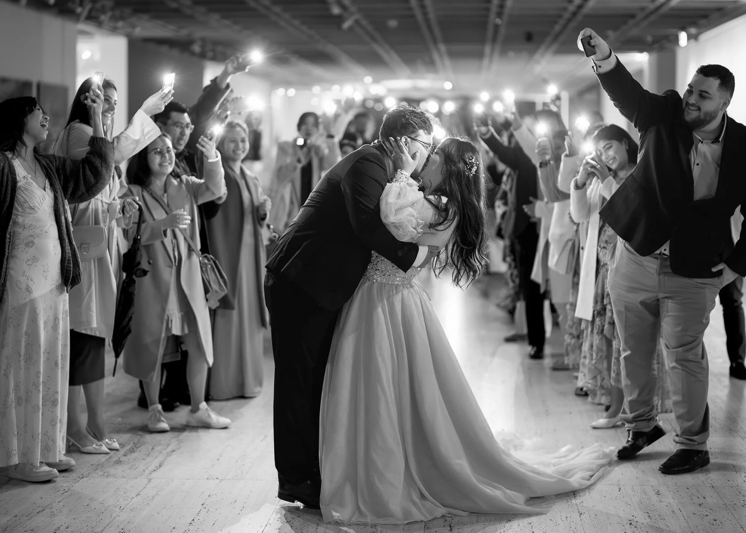 Bride and groom share a kiss surrounded by cheering guests during their Art Gallery Sydney wedding, captured by Hunter Valley wedding photographer.