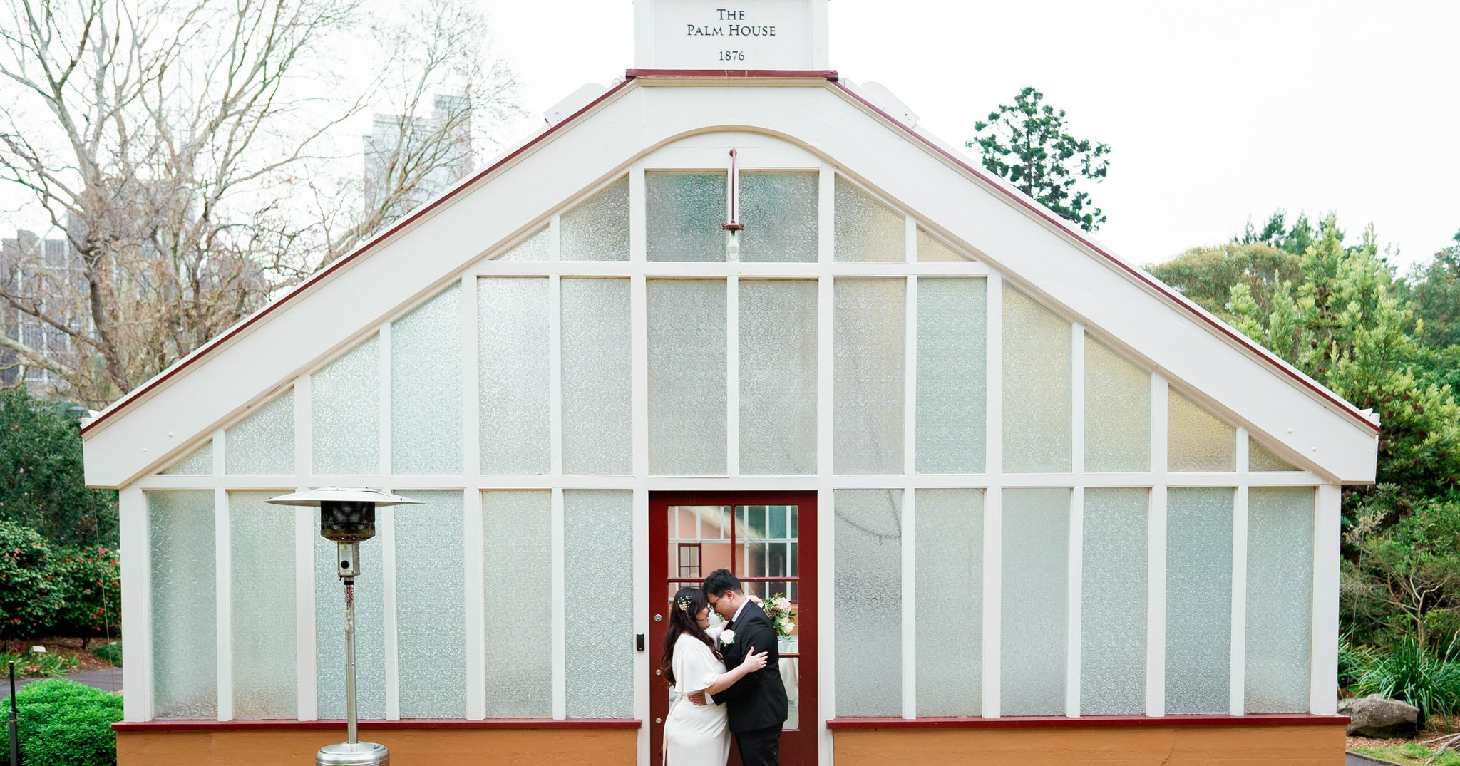 Bride and groom share a romantic moment in front of The Palm House at Botanic Garden Sydney, captured by Hunter Valley wedding photographer.