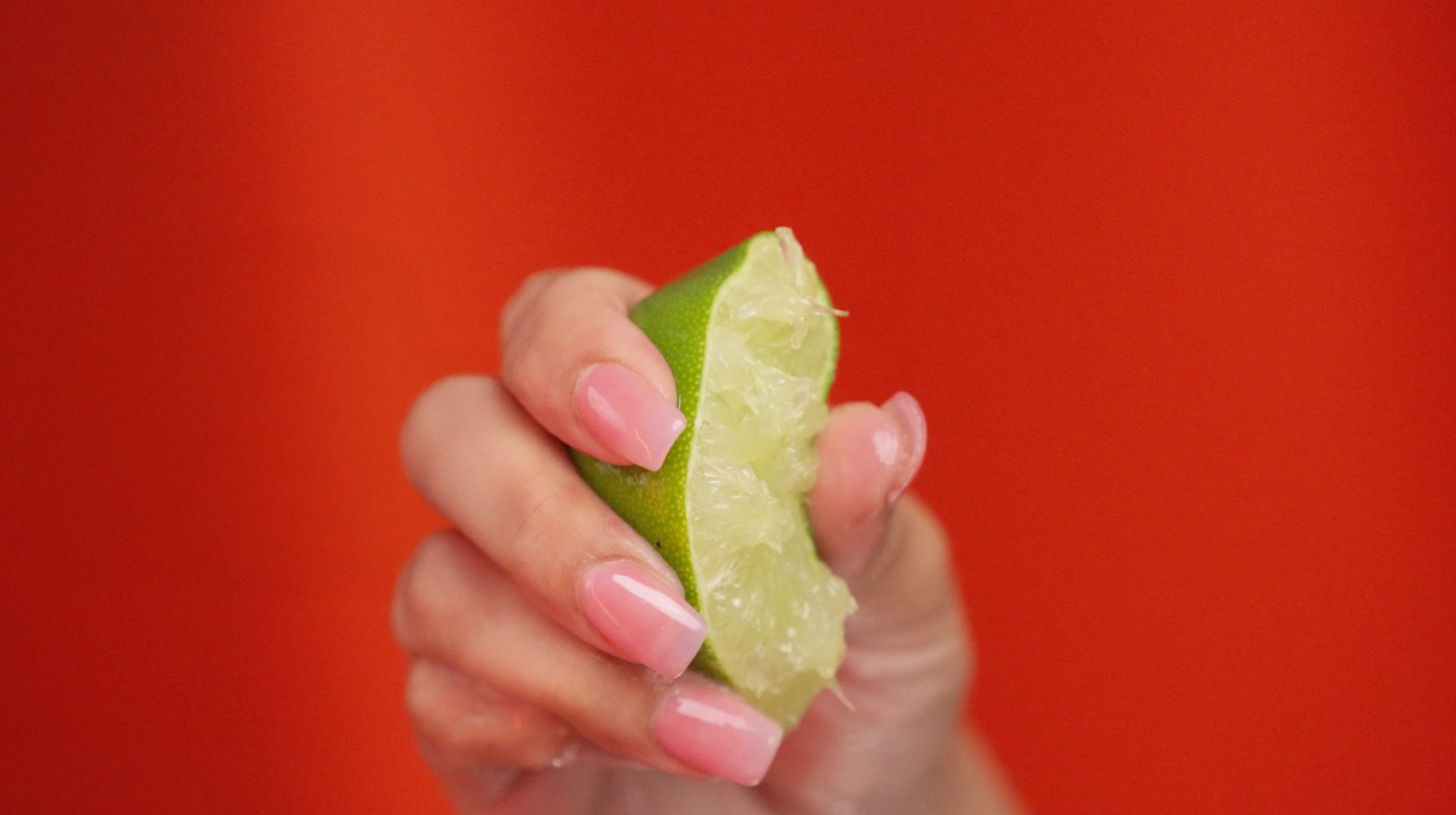 A man in a gray shirt writing on a whiteboard with a black marker, with a brick wall and surfboards in the background.