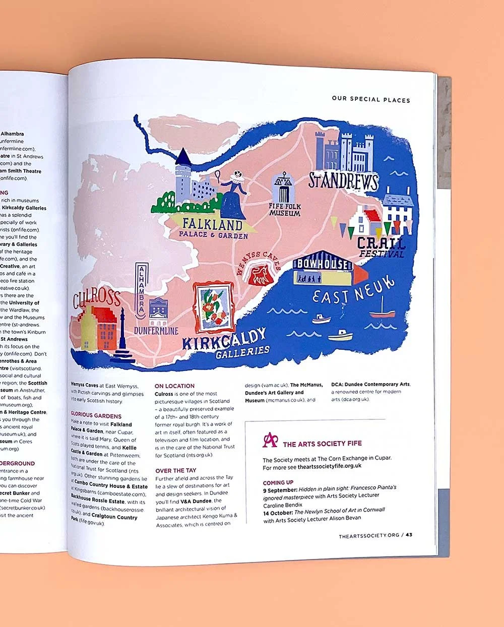 Photograph of a custom illustrated regional arts map of Fife by Anna Simmons, printed on a page in warm red, yellow, blue, and green on a pink background, showing sites such as St Andrews, Falkland Palace, Kirkcaldy Galleries, Culross and Crail.