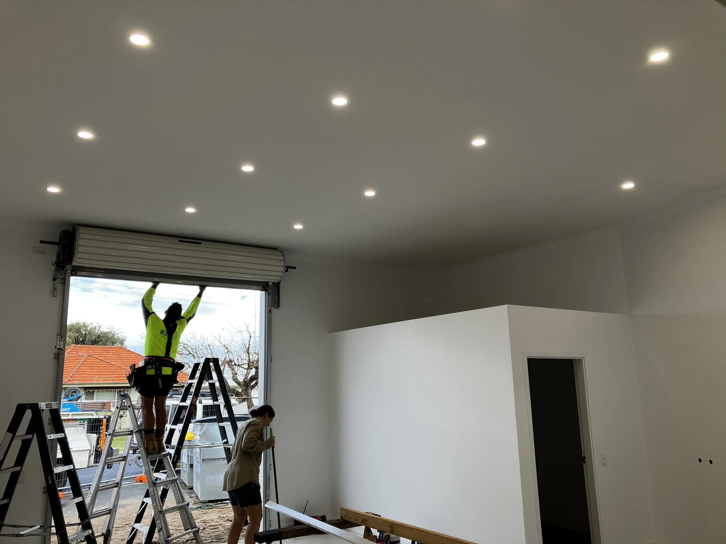 installing a large roller shutter in a residential garage with multiple ceiling lights