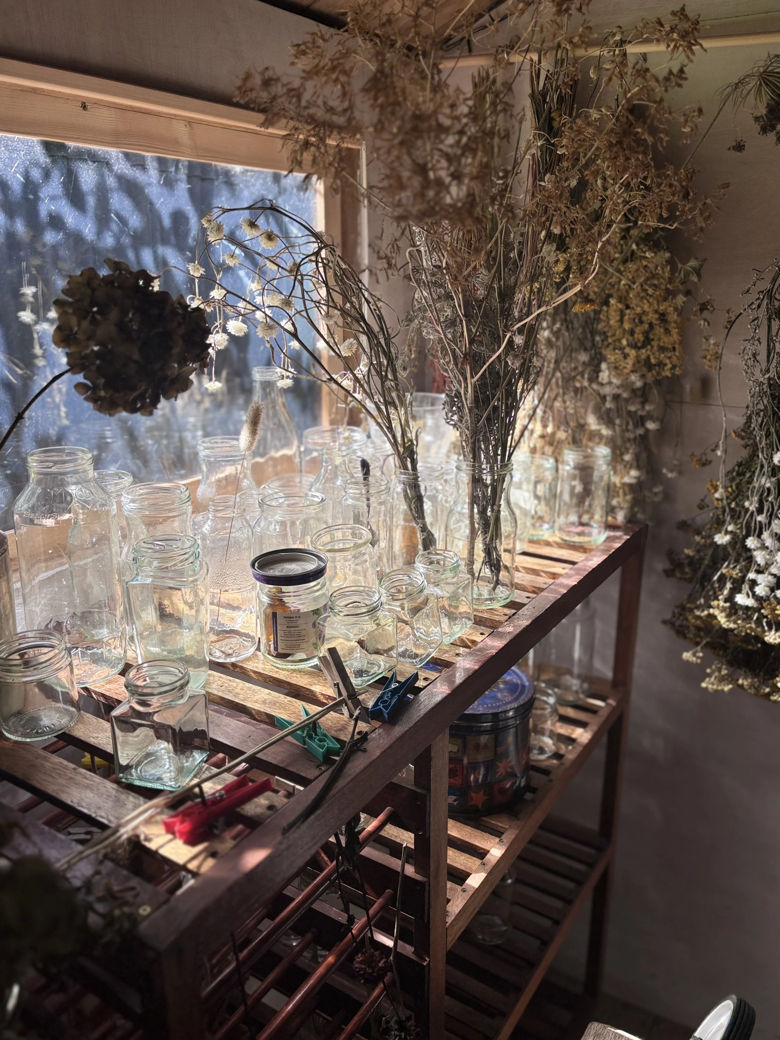 A Cornish maker’s workspace filled with dried flowers, glass jars and materials ready to be used.