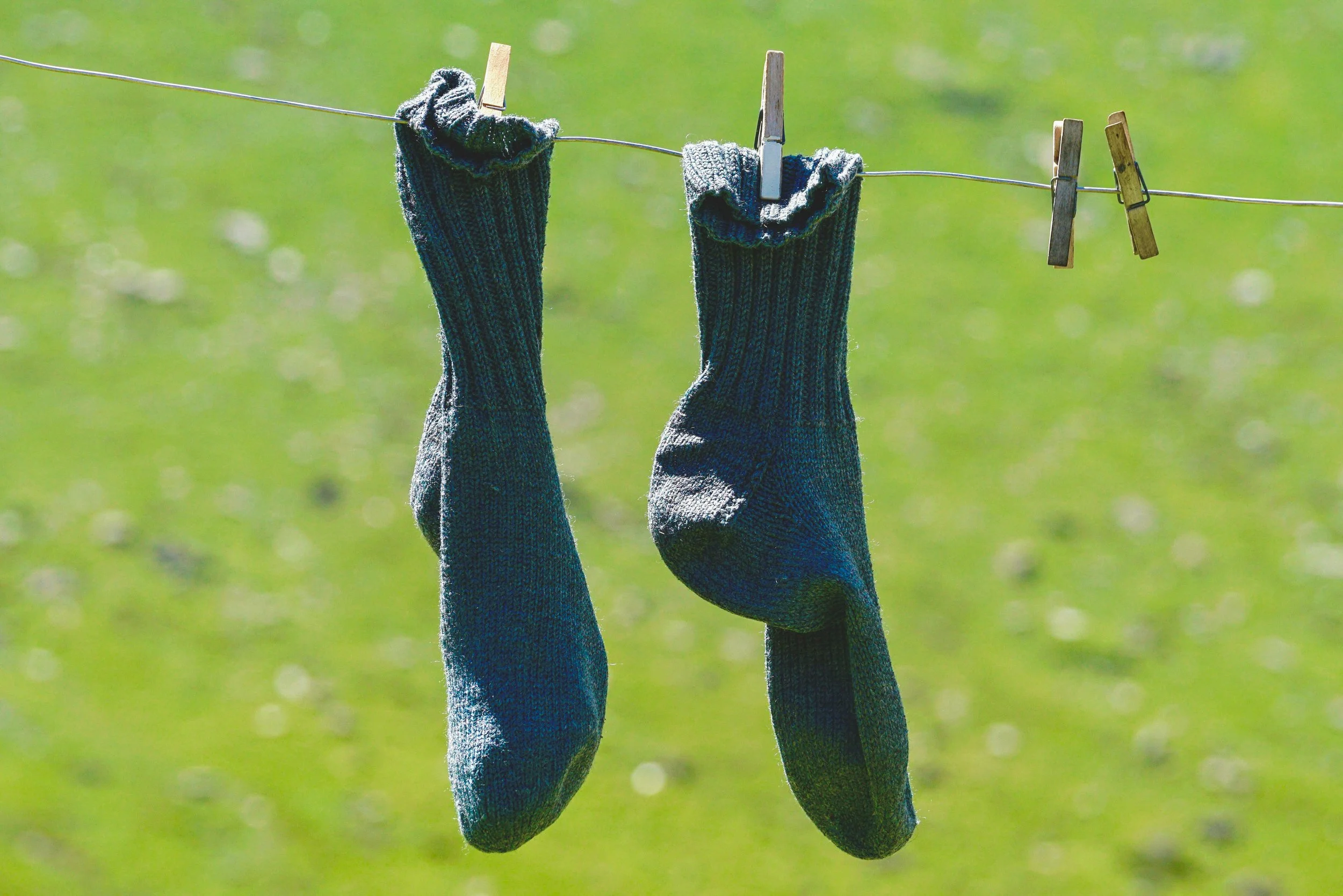 Washing line with a pair of blue socks pegged up against a clear blue sky, symbolising domestic life and simplicity.