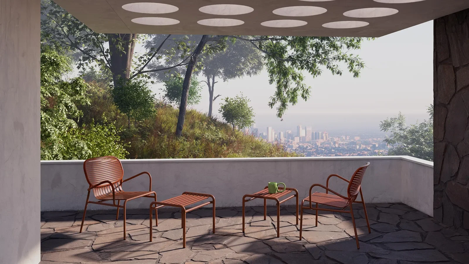 Outdoor patio with two orange chairs, a small matching table with green mugs, overlooking a hillside with trees and a cityscape in the distance