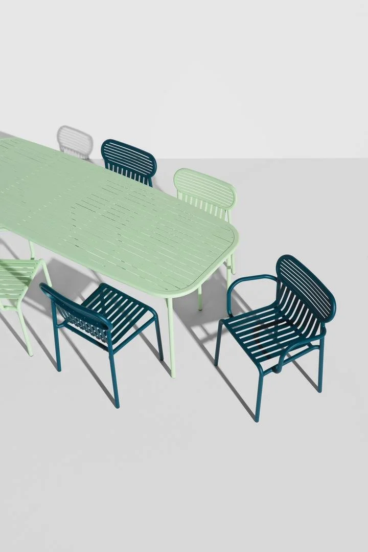 Colorful modern outdoor dining table with matching chairs in shades of green, blue, and white on a light gray surface.