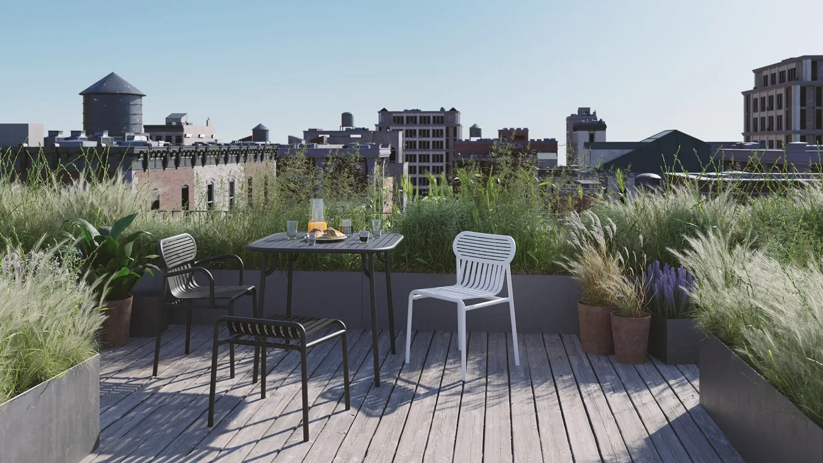 Rooftop balcony with a table set for breakfast, surrounded by potted plants and greenery, with city buildings in the background.