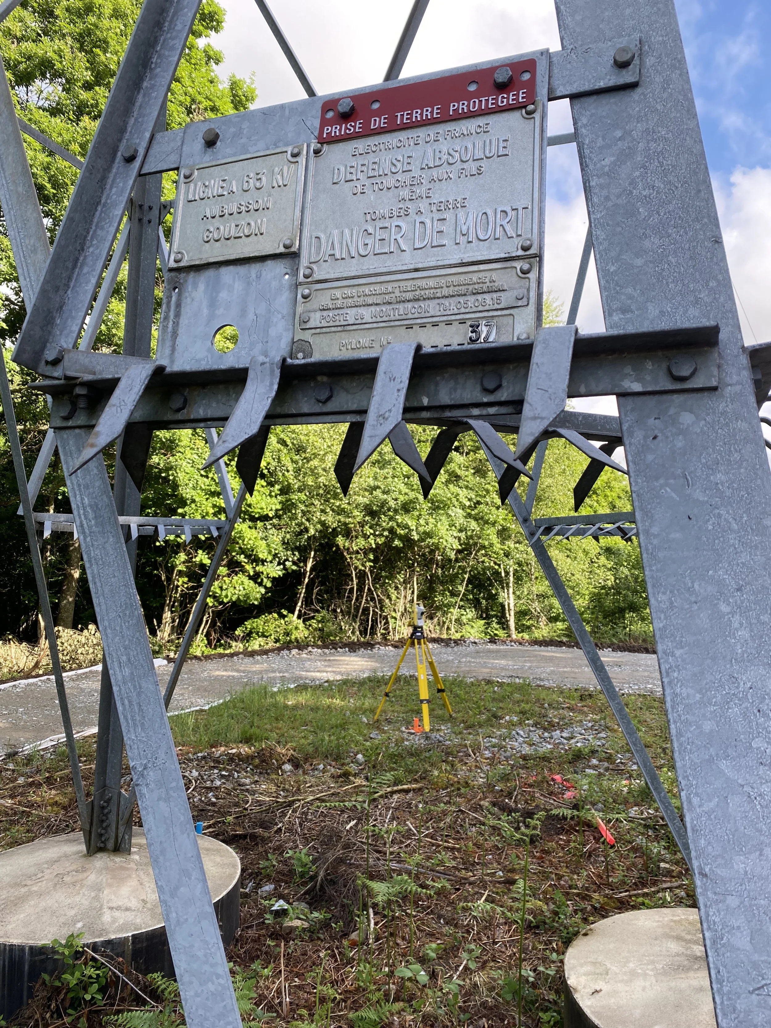 Poteau électrique avec panneau de sécurité en français, indiquant la prise de terre protégé. 
Lebon Services - votre prestataire pour vos chantiers de lignes électriques haute tension.