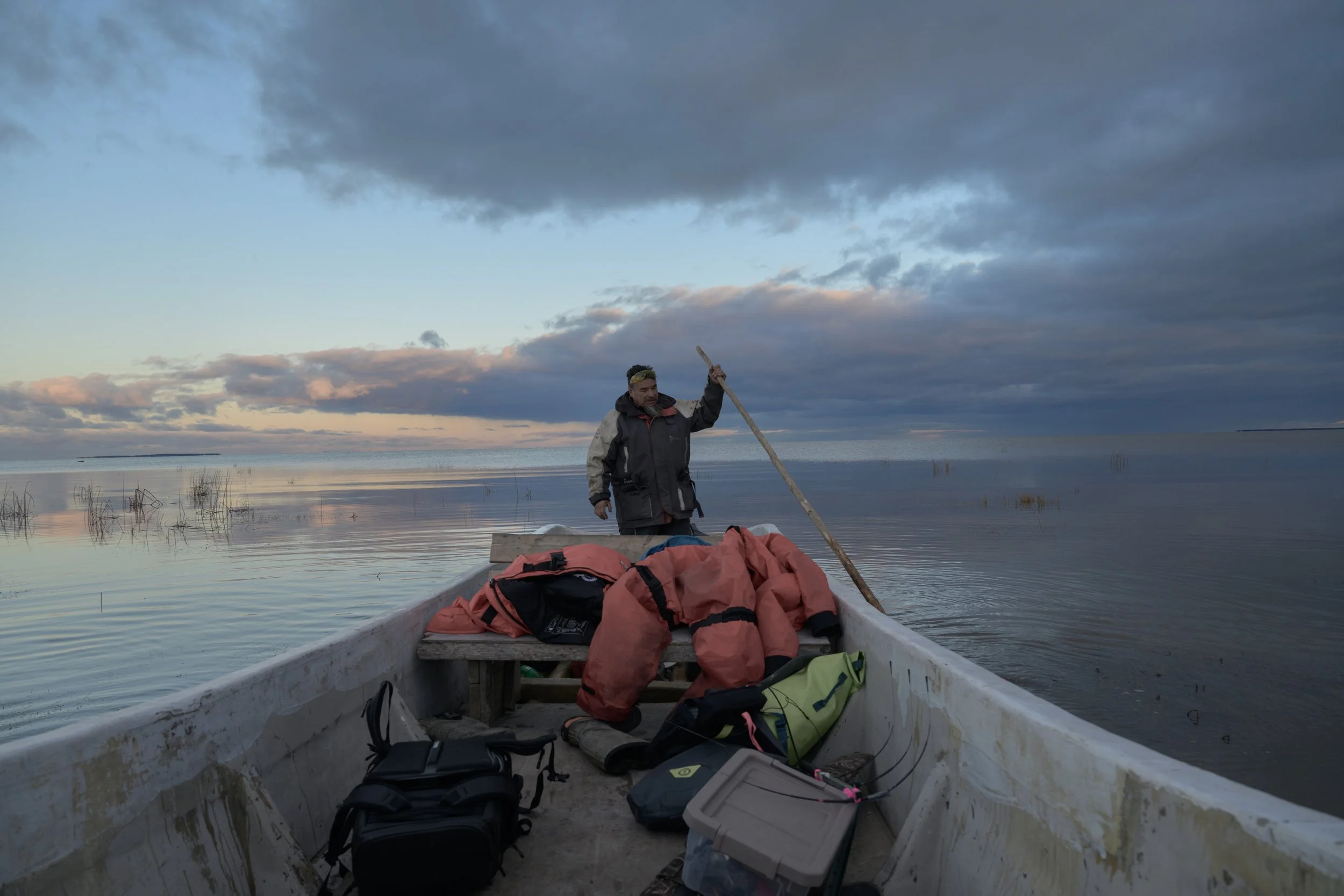 Boat captain using a pole to guide the boat through the shallow waters of Rupert Bay.