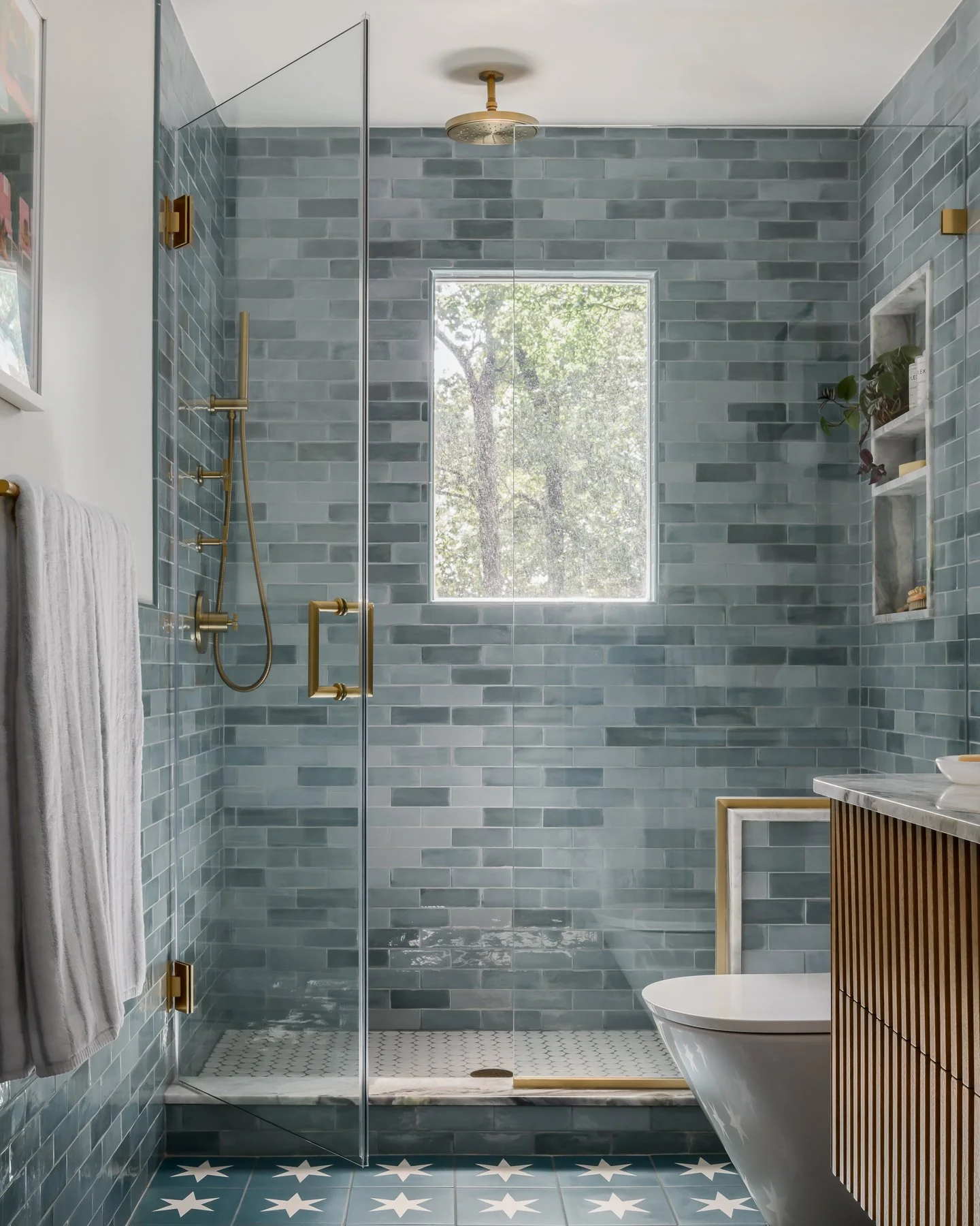 ✨ Bathroom goals ✨
This bathroom was a dream project for clients who aren&rsquo;t afraid to take risks. From the star-patterned floor tile to the watery blue-green shower walls, the custom oak fluted vanity, and brass accents, every choice reflected 
