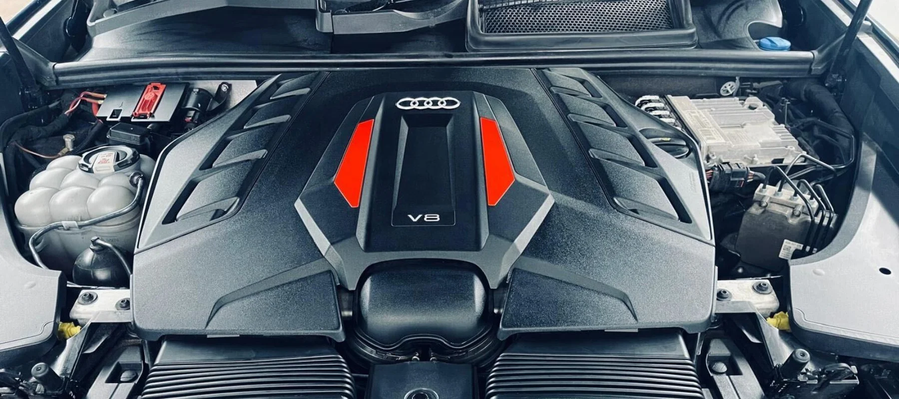 Front engine bay of an Audi vehicle with a visible V8 engine, some components, and wiring.