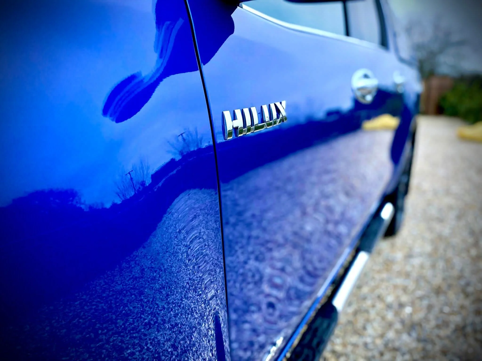 Close-up of a blue Toyota Hilux truck with the model badge visible on the side.