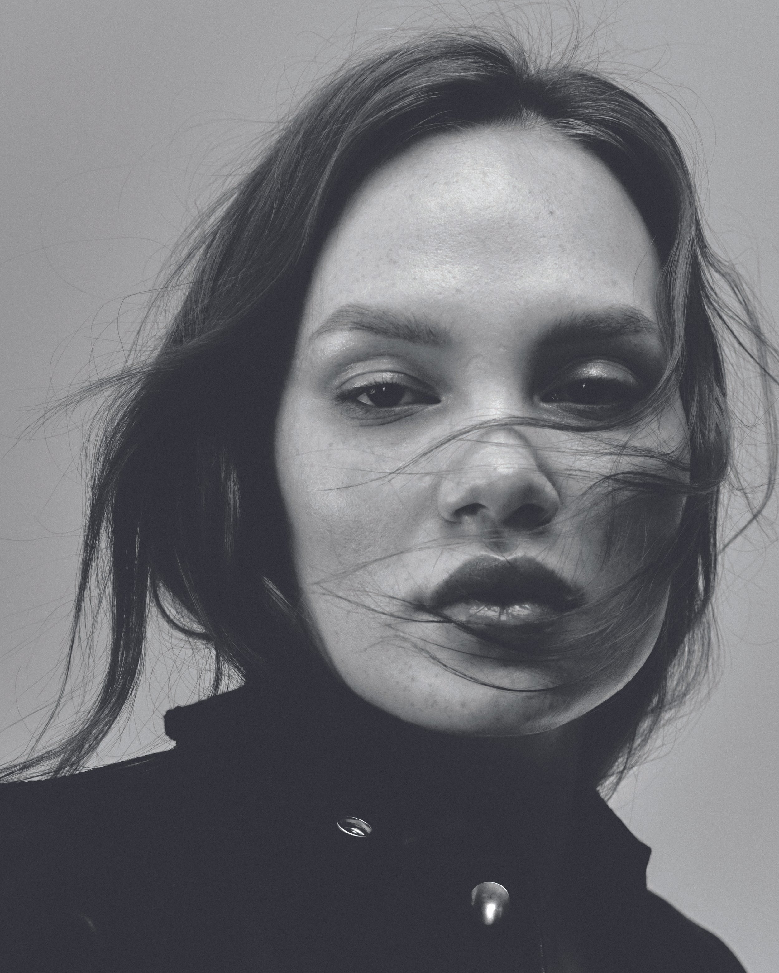 Black and white portrait of a woman with straight, dark hair, wearing a high-collared top with buttons.