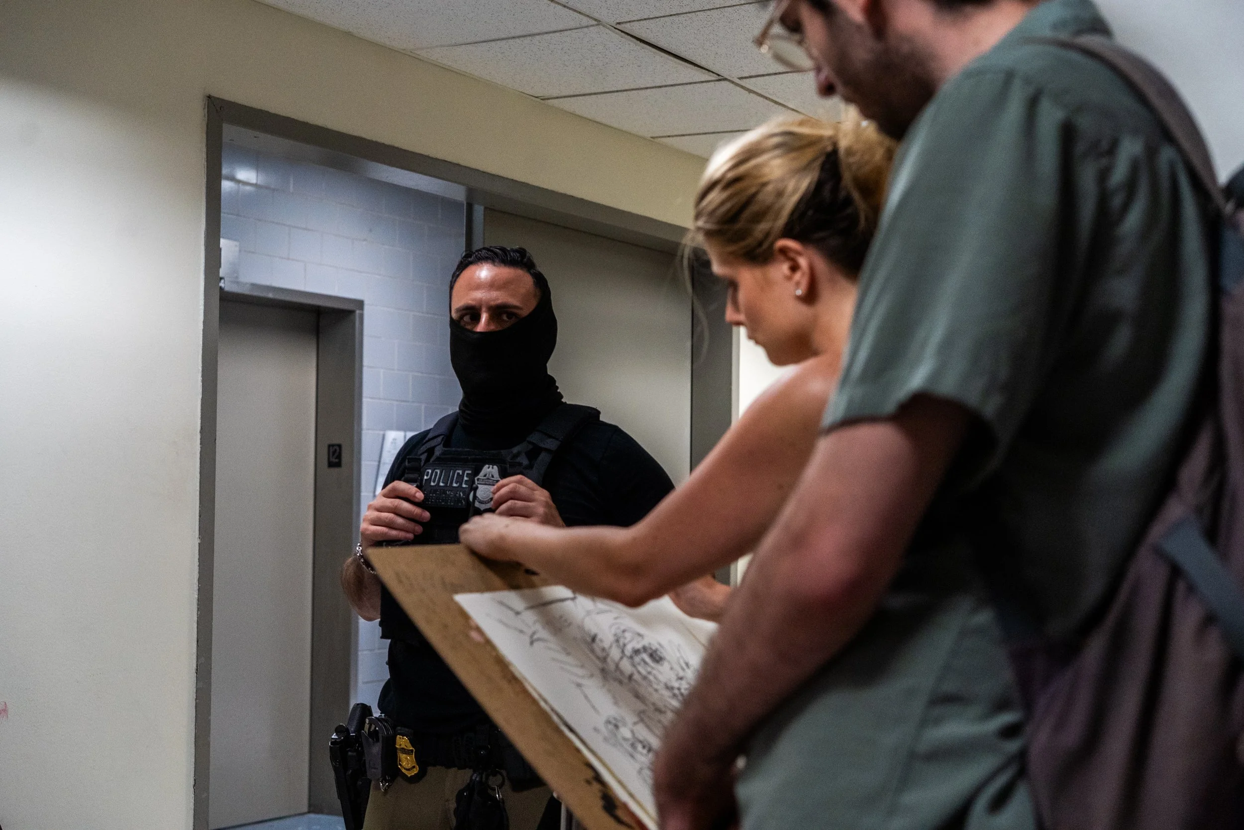 A court sketch artist draws one of the ICE agents as he watches silently.