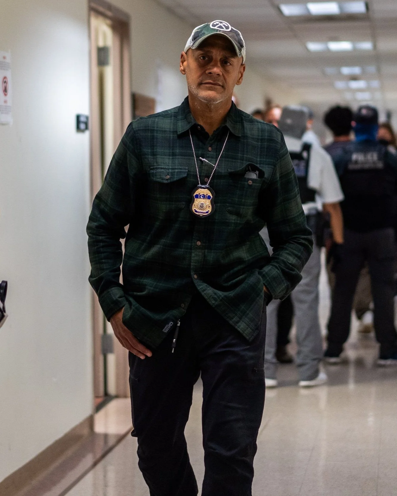An ICE agent walks toward the camera.
