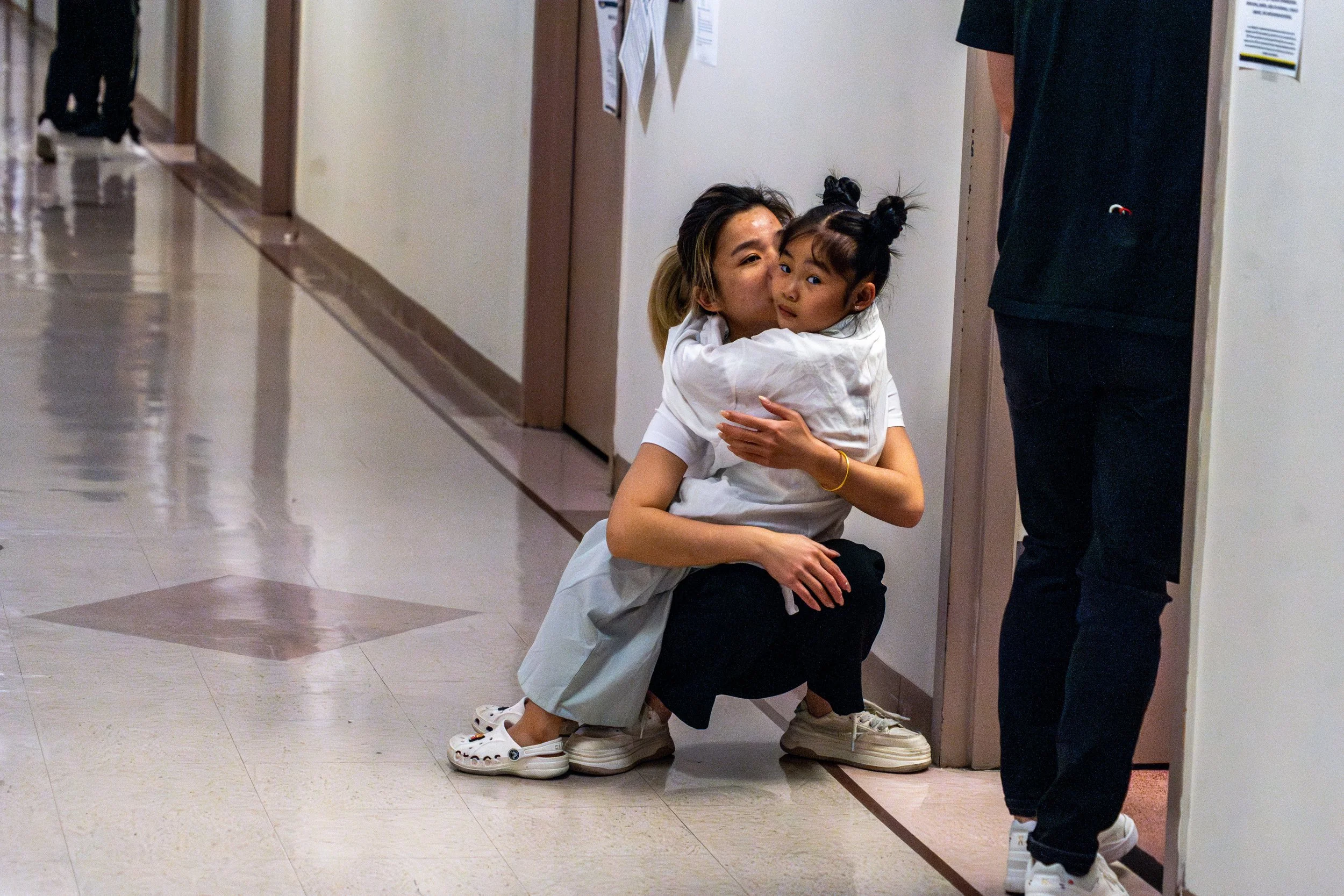 A mother crouched to hold her daughter close, just outside the courtroom doors. Thankfully neither of her parents were taken and they were free to leave after their individual hearing took hours.