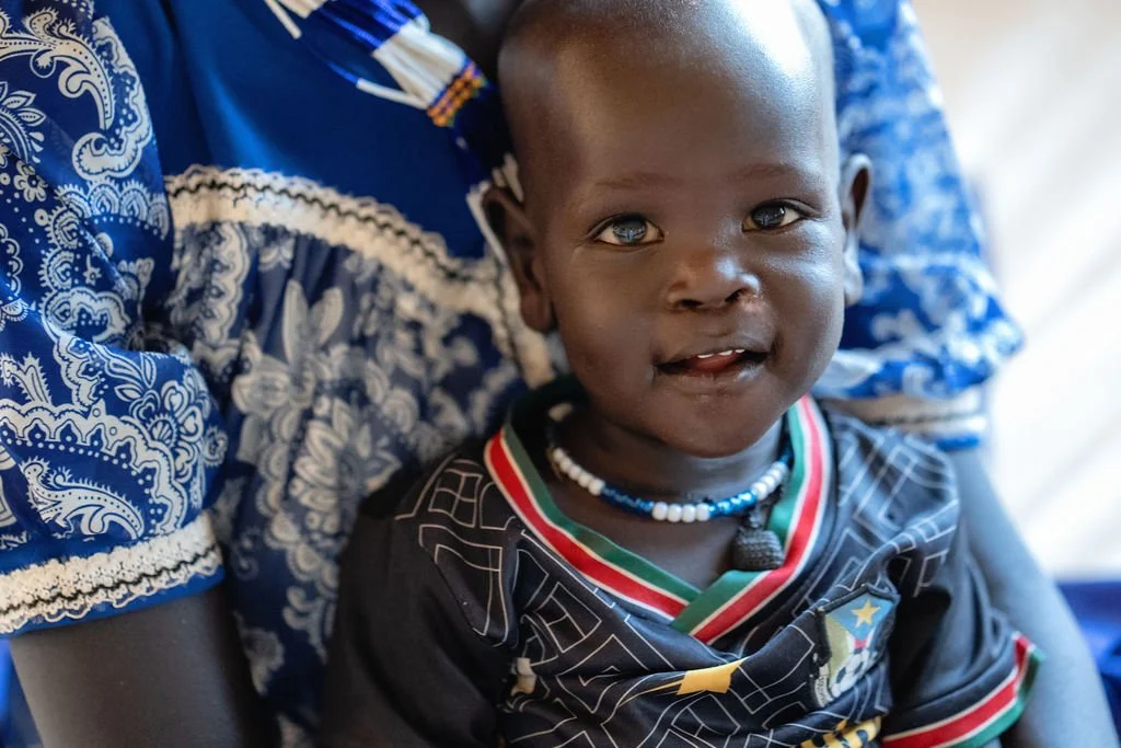 A newly built single-story beige house with a red-tiled roof, several windows, and a person standing outside near some construction materials.