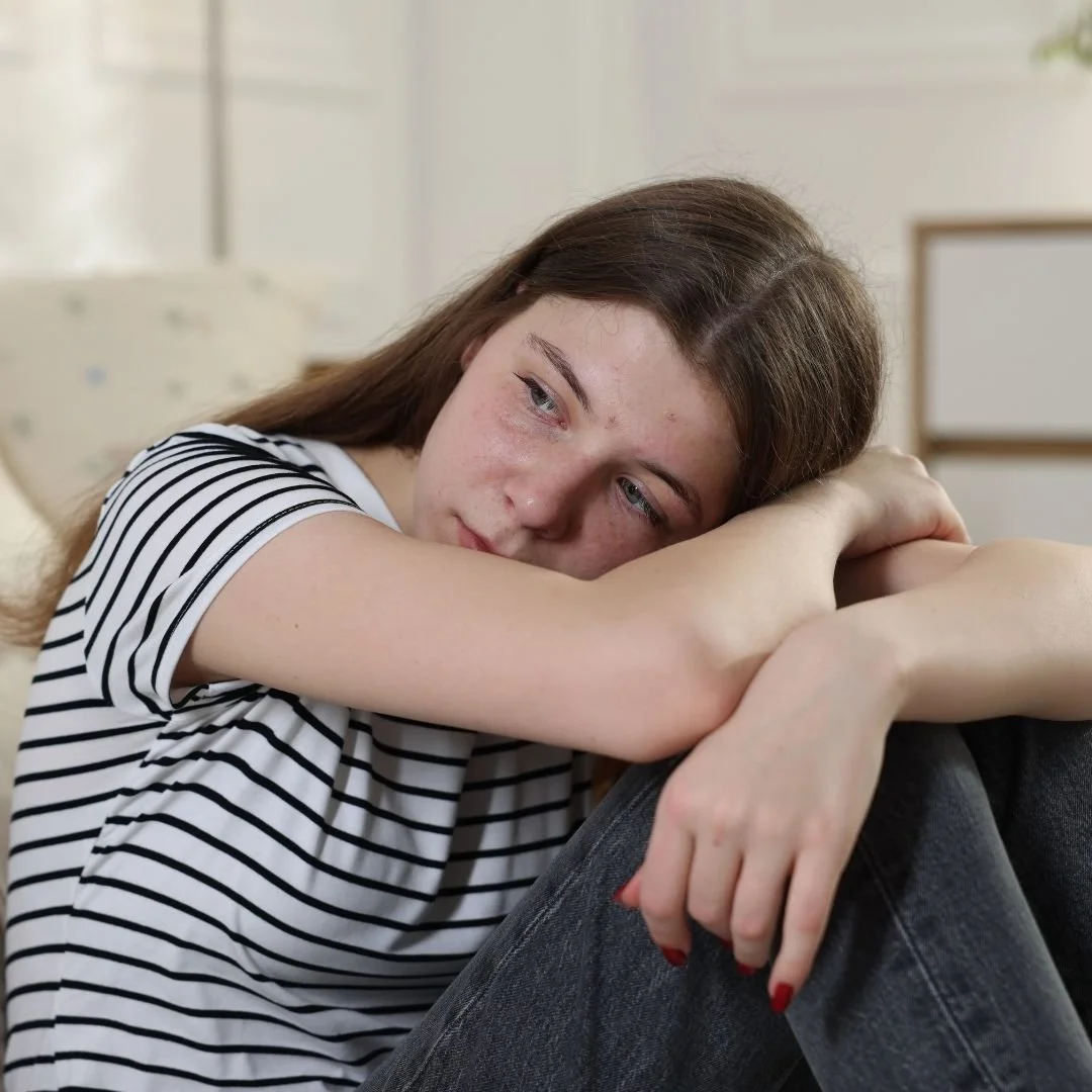Depressed teenage girl sitting alone with head down, illustrating why ignoring mild depression can lead to major episodes and highlighting the importance of early mental health support for teens.