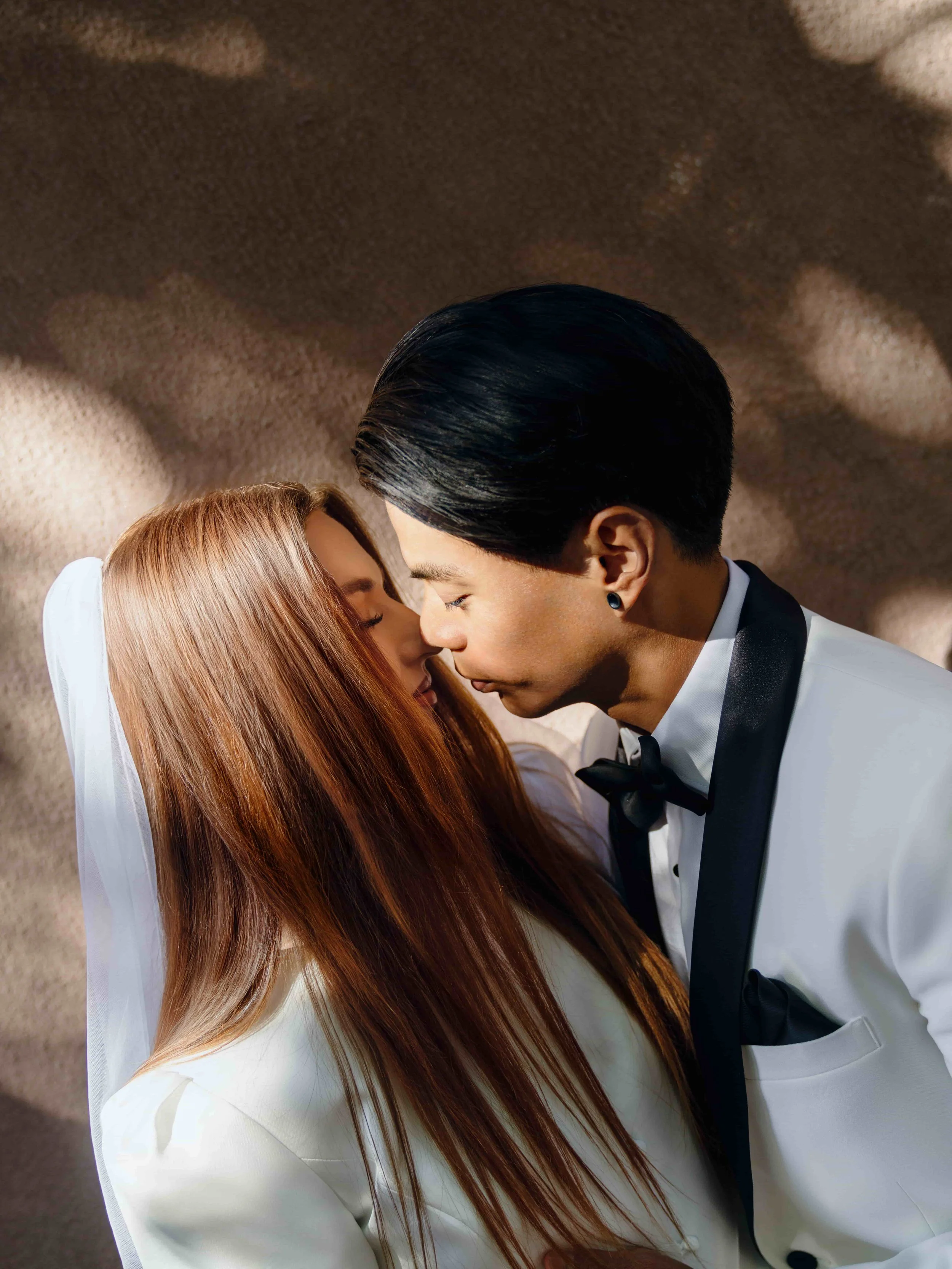 A groom and bride in wedding attire with their Foreheads touching and eyes closed