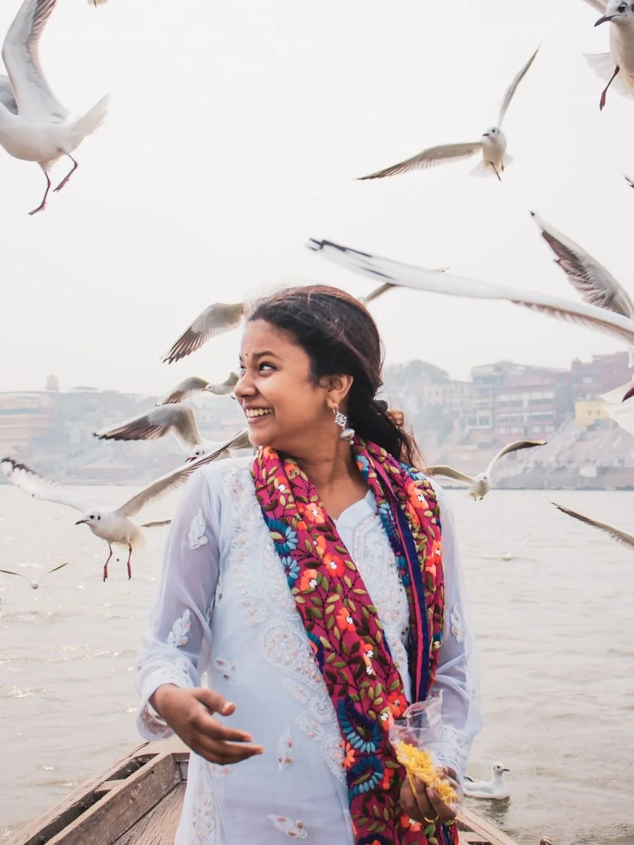Woman standing on a dock with seagulls flying around