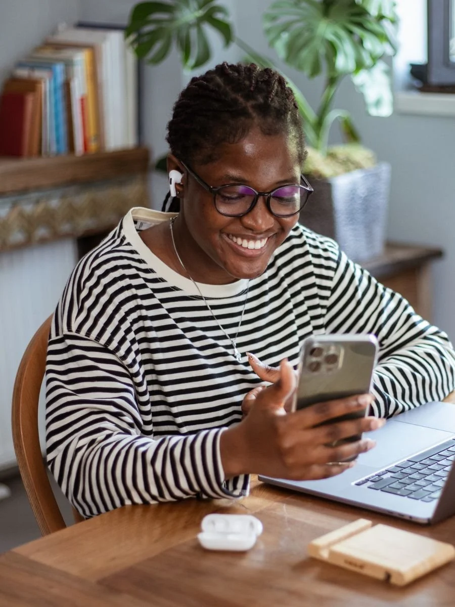 Young black woman smiling at her phone