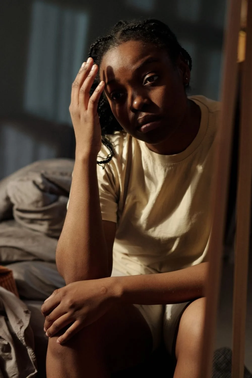 Young woman sitting alone at the end of the bed