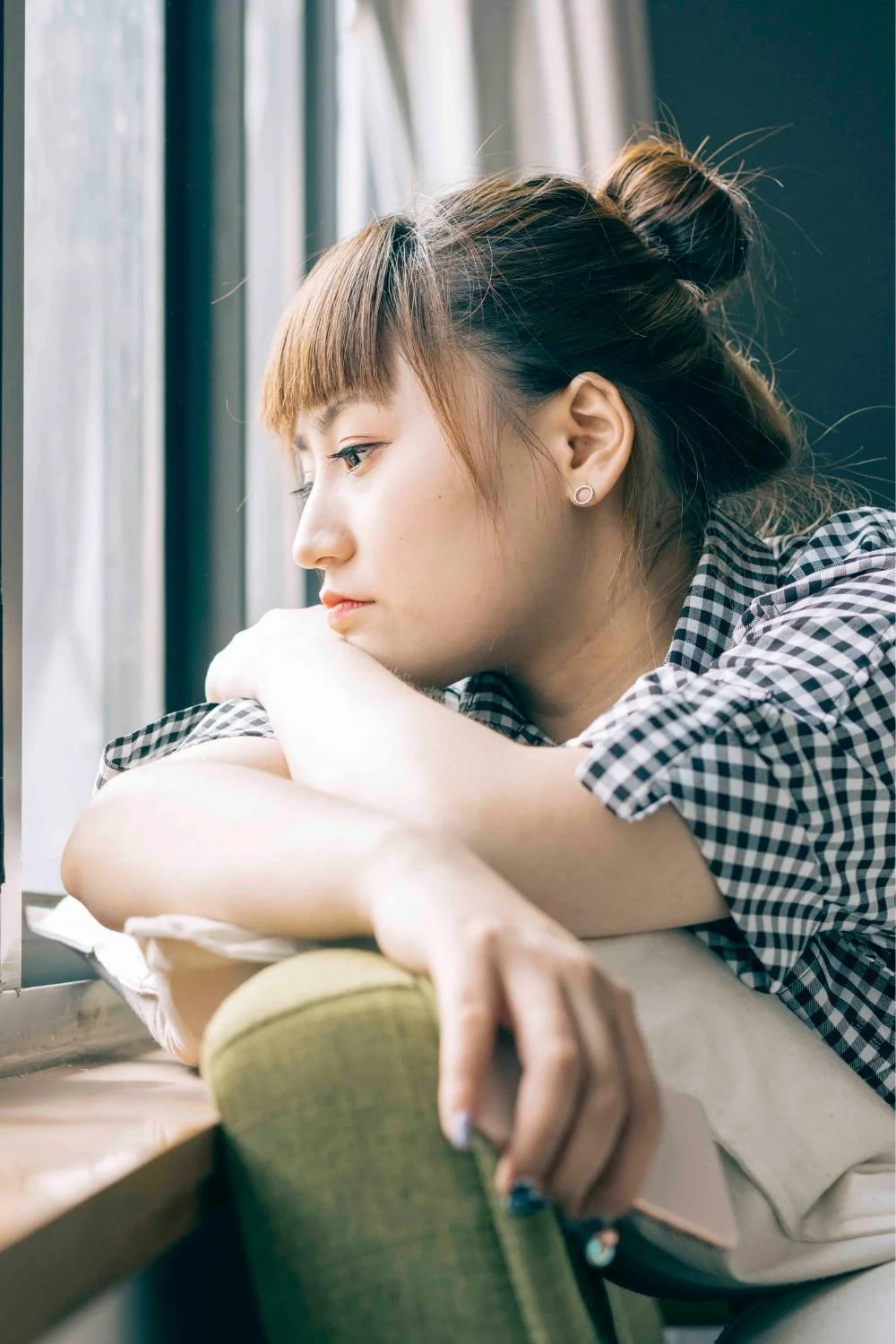 Lonely young woman looking out a window