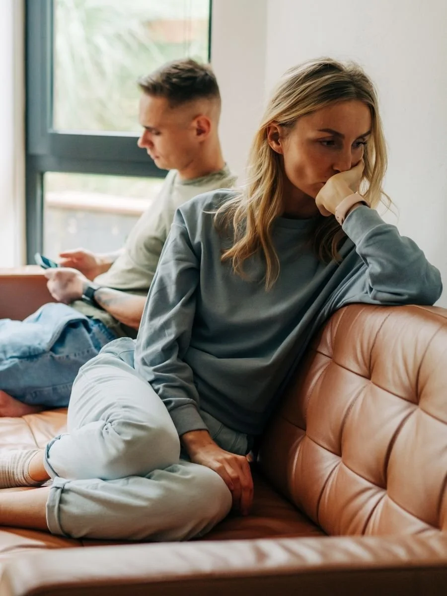 Woman sitting next to her partner struggling with conflict avoidance