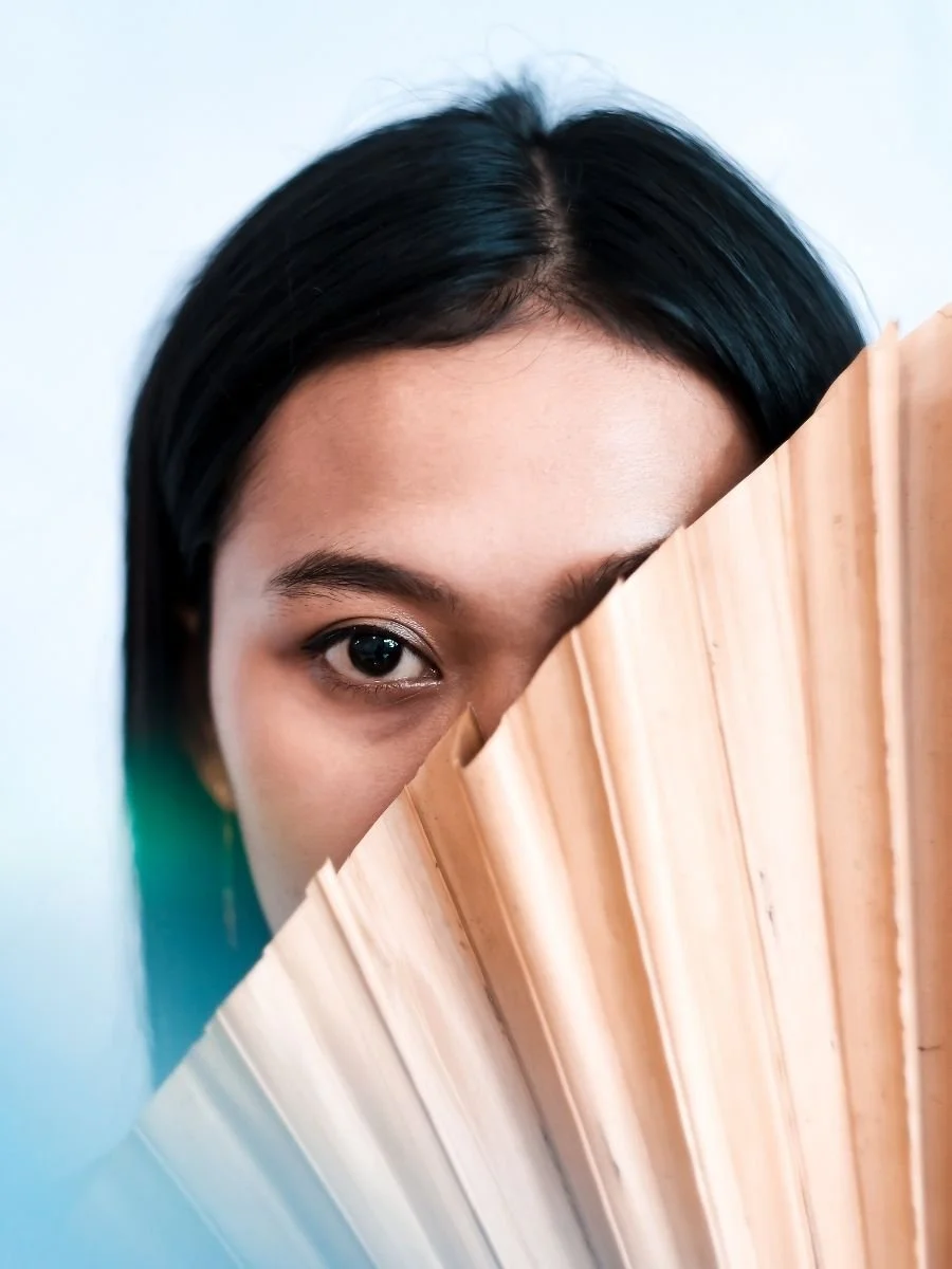 Woman hiding part of her face behind a palm leaf