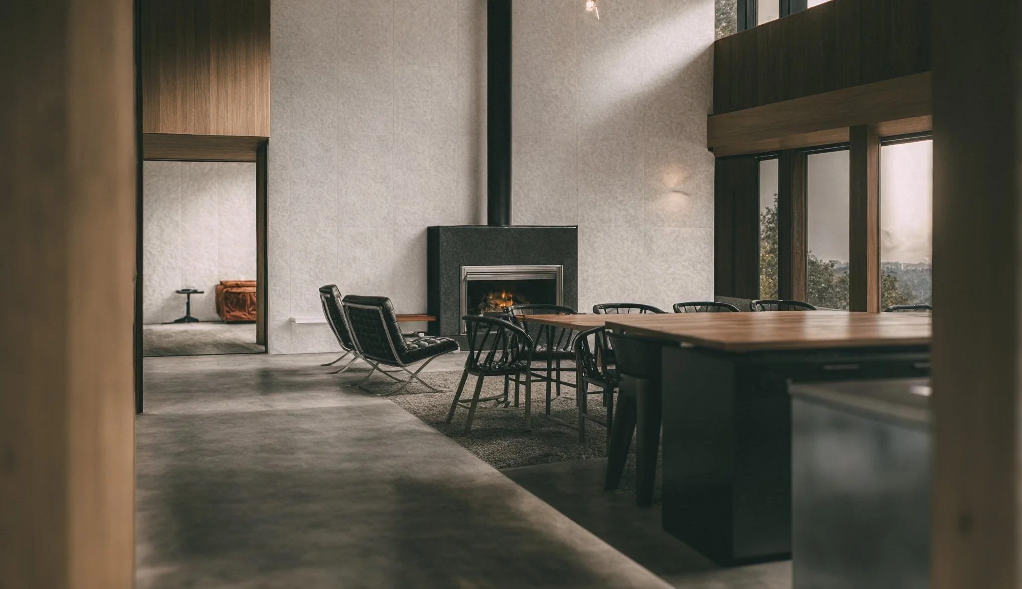 Salon moderne avec cheminée, grande table en bois et chaises, murs en pierre et fenêtres avec vue sur la nature.