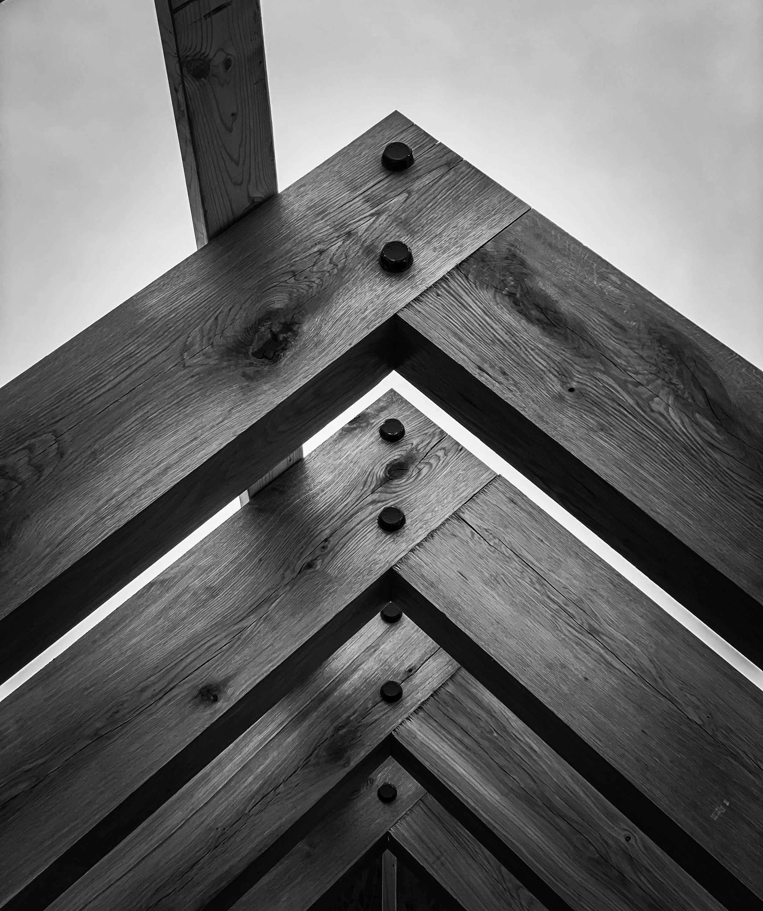 Vue en contre-plongée de structures en bois assemblées avec des boulons noirs
