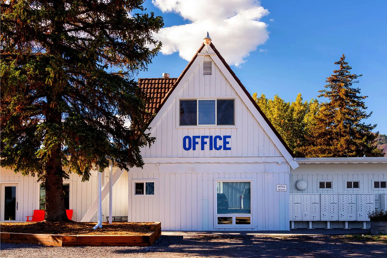 Tiny Town leasing office, a white A-frame building with blue "Office" channel letters

Tiny Town's leasing office occupies a white A-frame building identified by bold blue channel letters, with resident mailboxes along its side wall.
