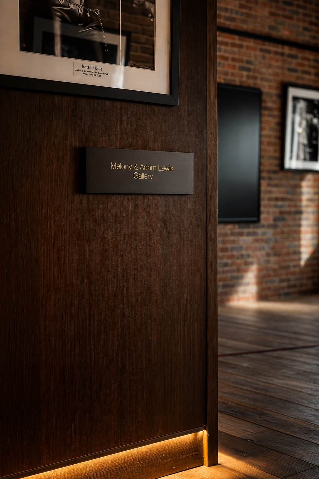 Melony & Adam Lewis Gallery donor plaque beside archival Natalie Cole performance photo Caption: Named donor gallery plaque for the Melony & Adam Lewis Gallery at the Paul JAS Center, installed beside an archival photograph documenting a past JAS Jaz
