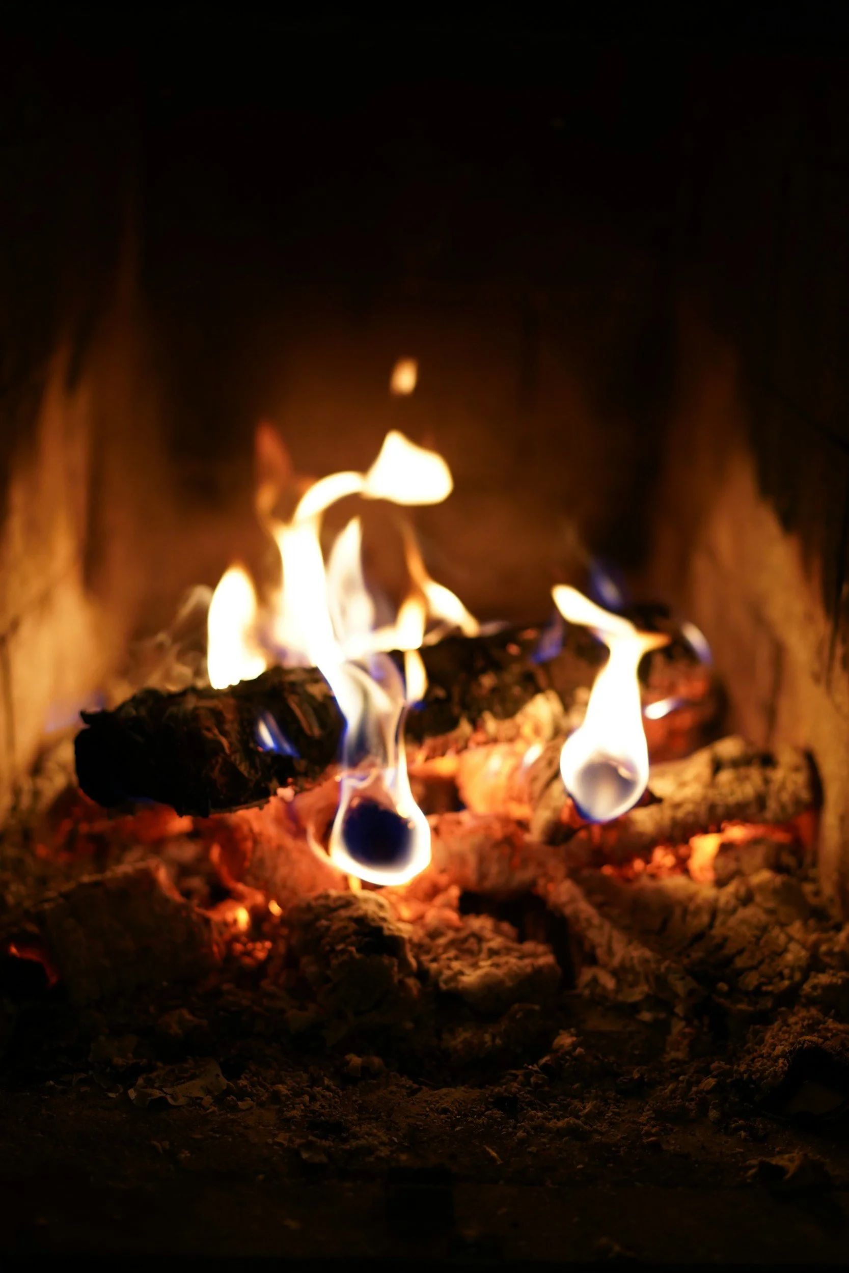 Burning firewood in a fireplace with flames and embers.