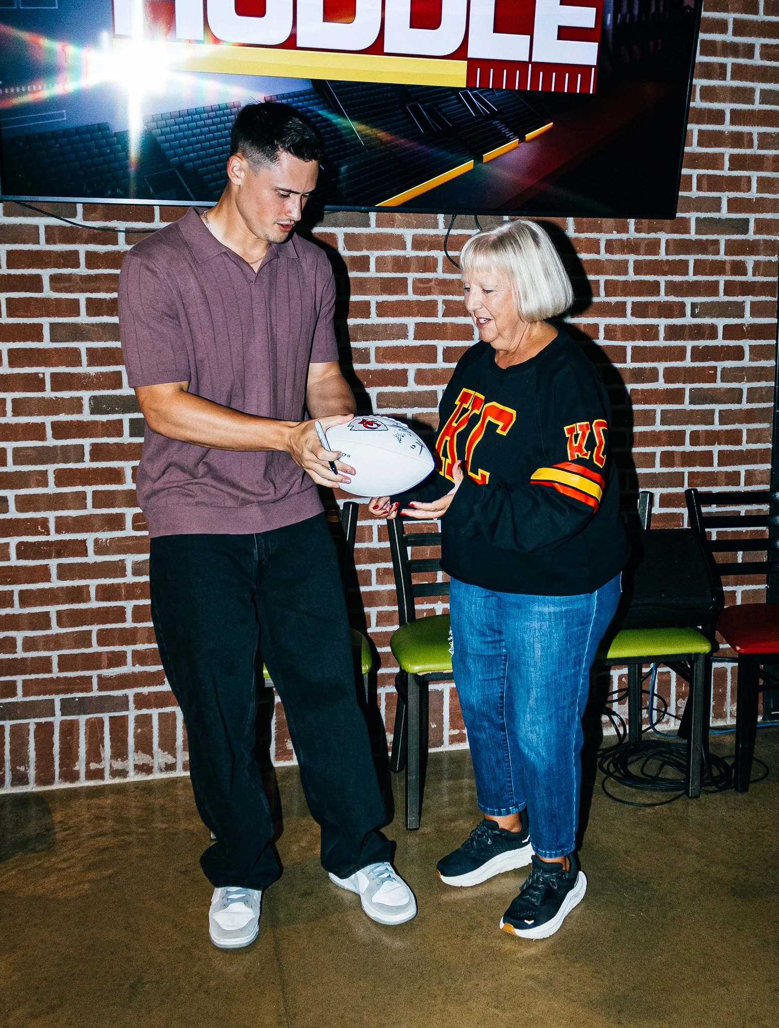 Matt Araiza signing a football for a fan during Kansas City Huddle at Chicken N Pickle Overland Park