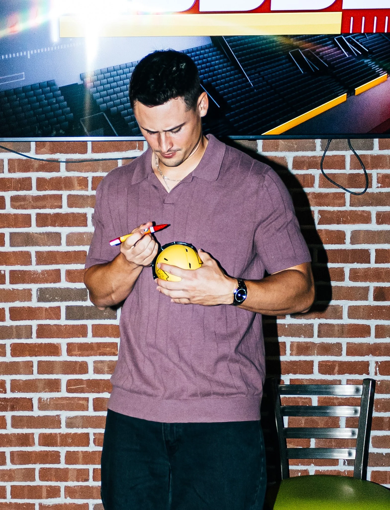 Matt Araiza signing a mini helmet during Kansas City Huddle at Chicken N Pickle Overland Park