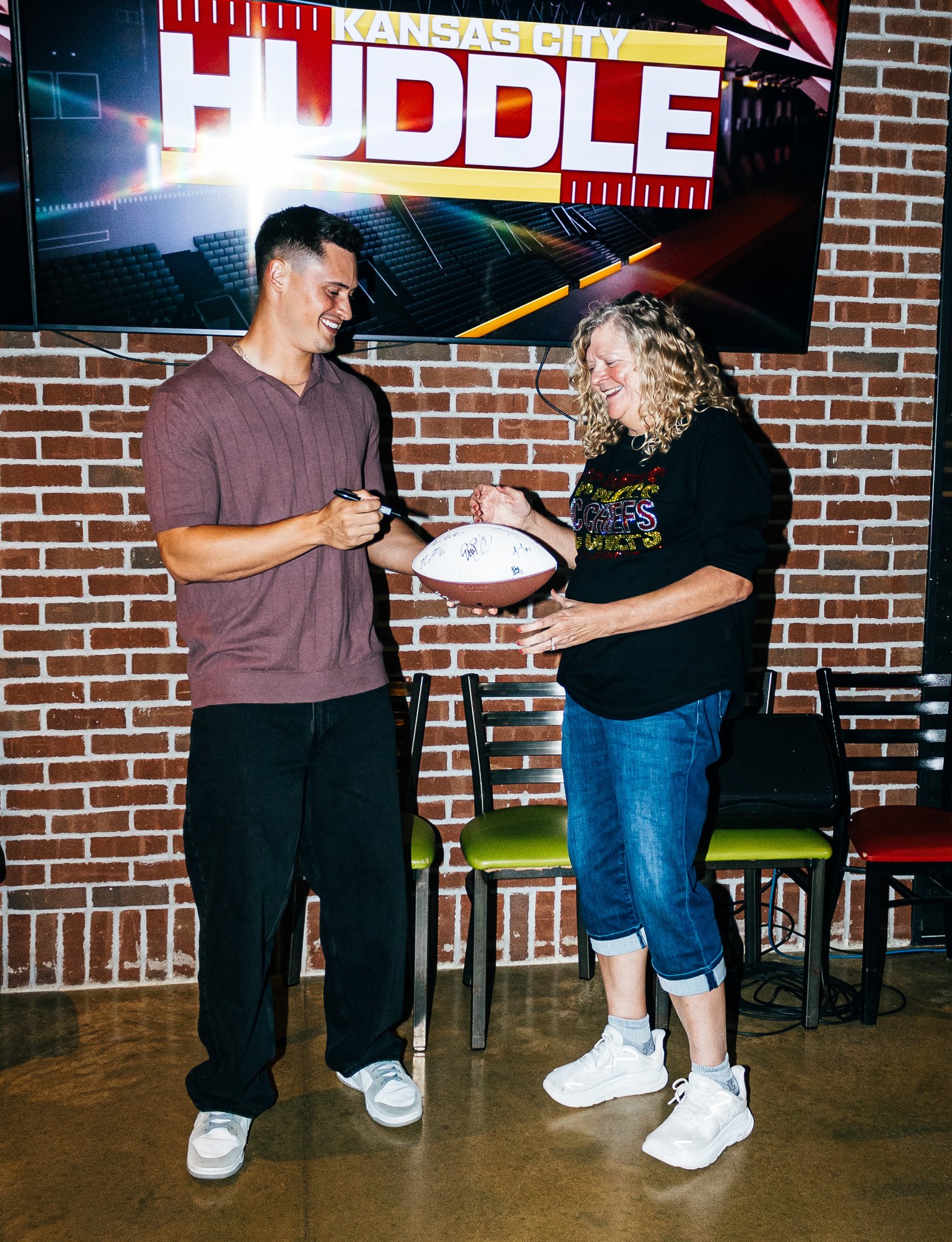 Matt Araiza signing a football for a fan during Kansas City Huddle