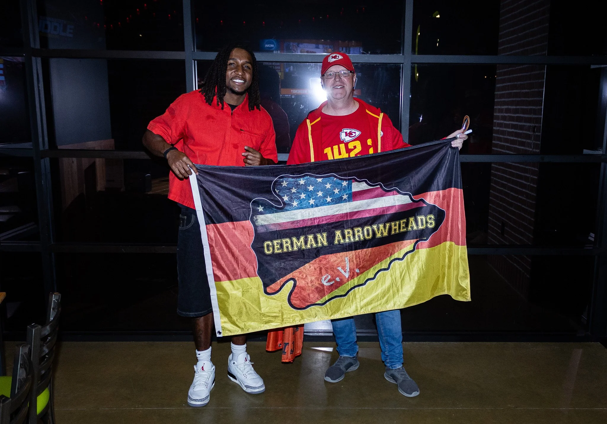 Nohl Williams and a fan hold up a German Arrowhead flag during the meet & greet for Kansas City Huddle