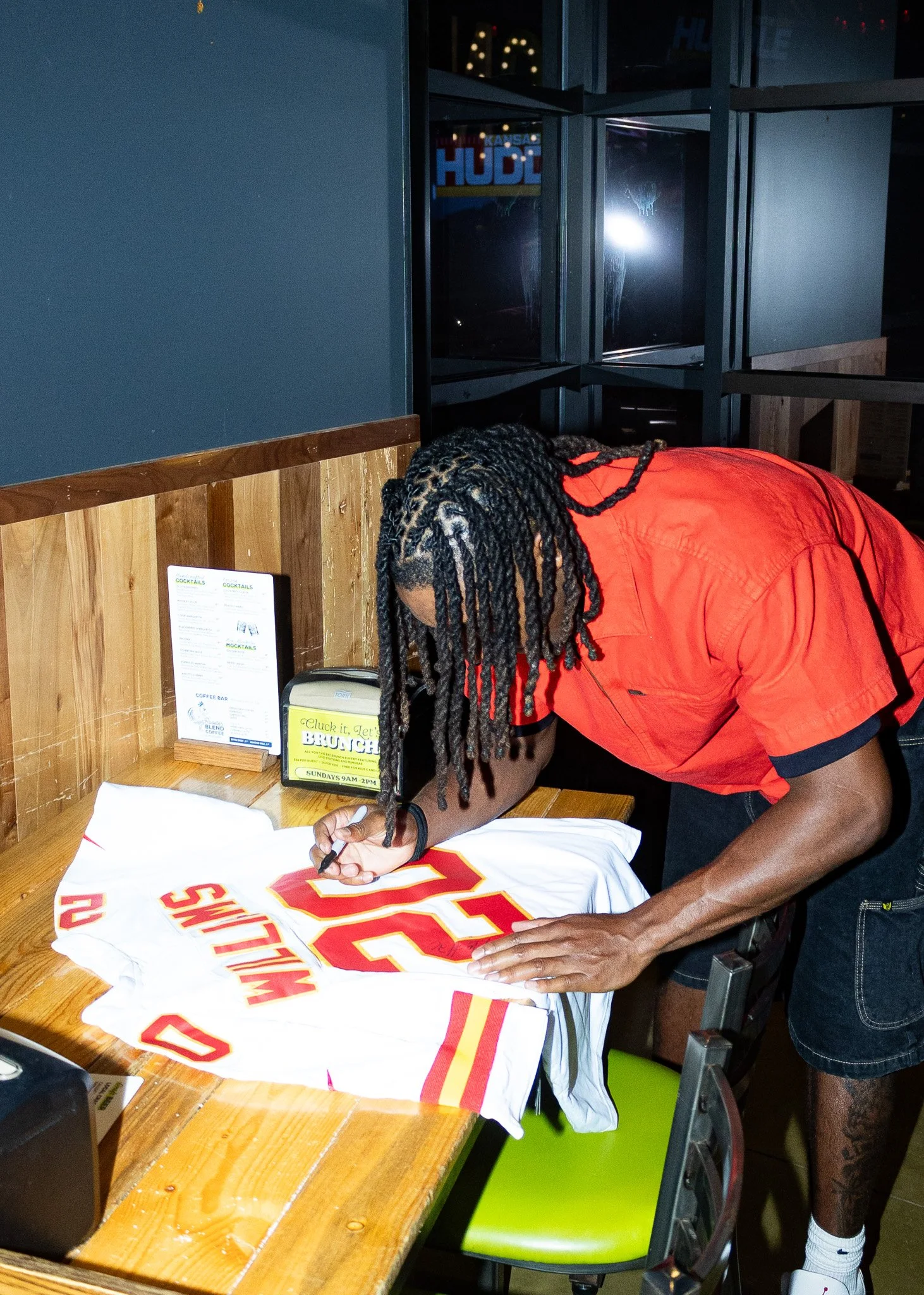 Nohl Williams signs a jersey during Kansas City Huddle live at Chicken N Pickle Overland Park
