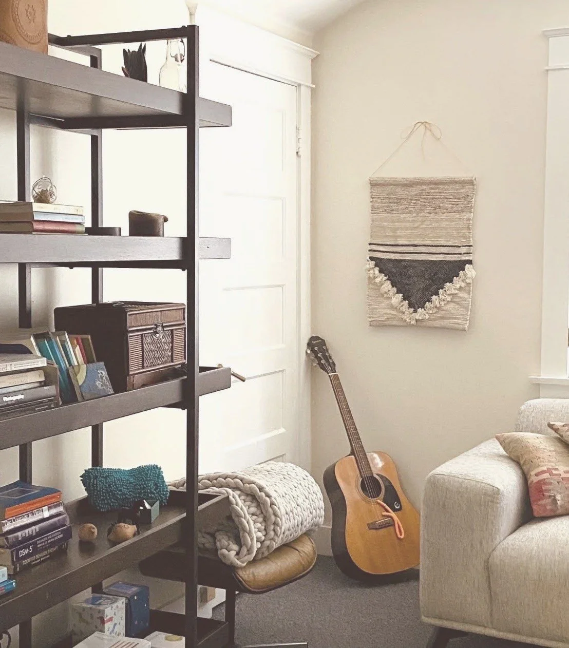 Therapy office in South Pasadena with a beige sofa, guitar, bookshelf, and woven wall hanging.