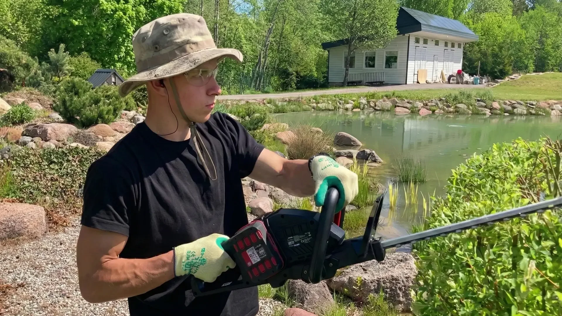Vyrukas karpantis margalapį gluosnį akumuliatorinėmis gyvatvorių žirklėmis.
