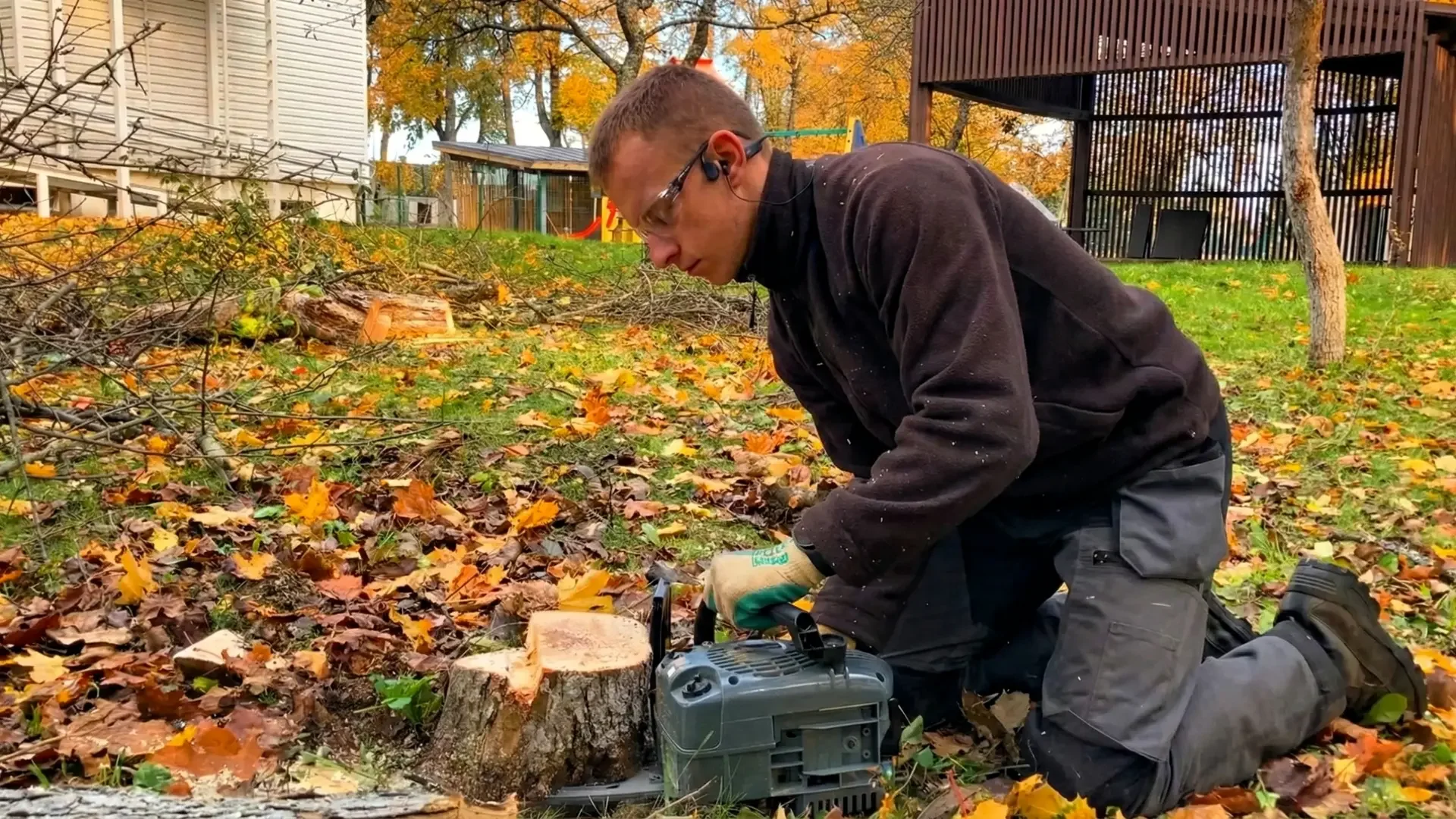 Vyrukas pjaunantis obels kelmą grandininiu pjūklu.