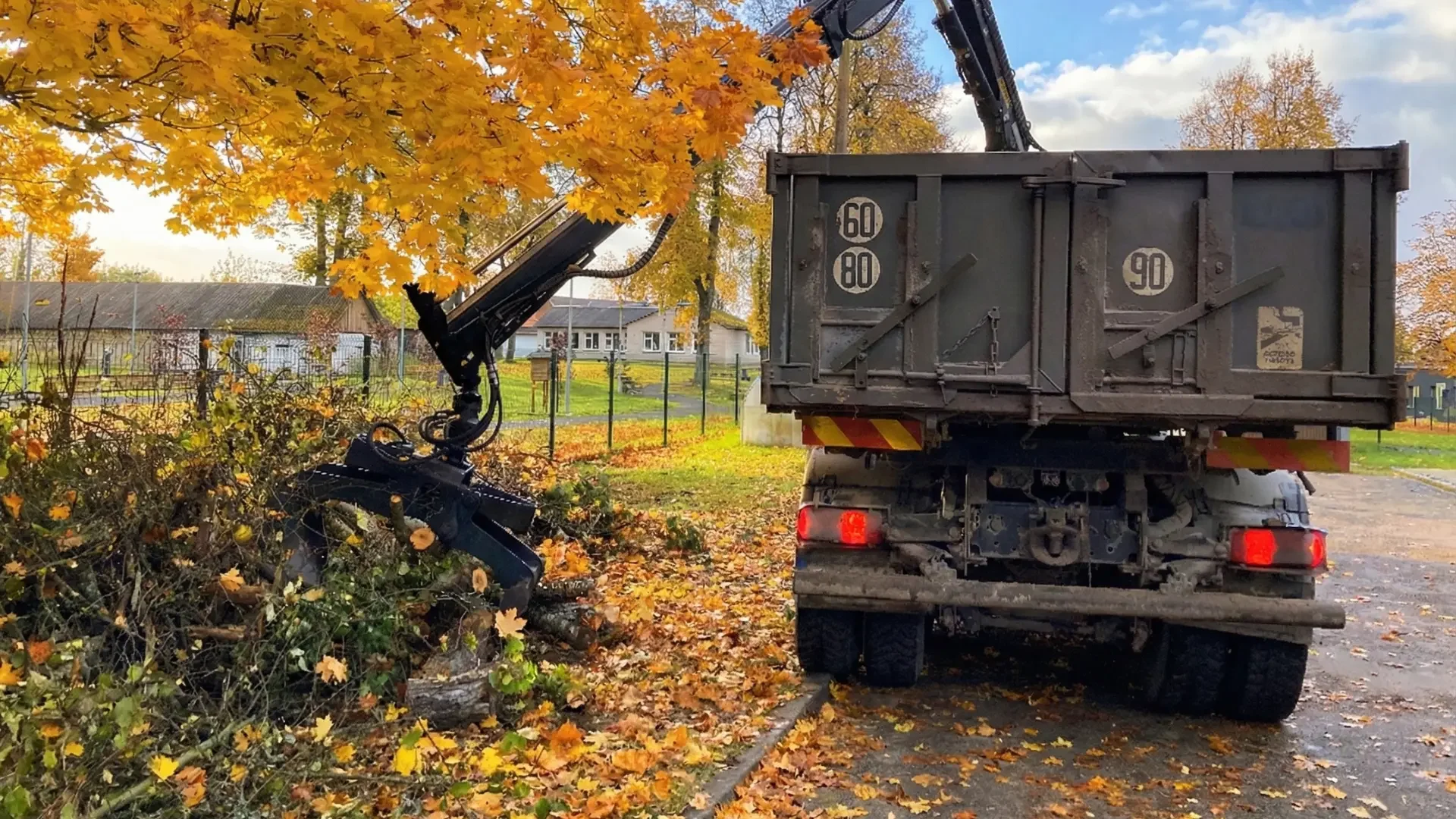 Sunkvežimis su fiskaru besikraunantis žaliasias atliekas.