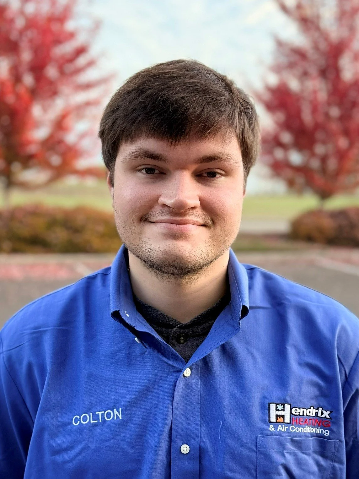 Person in a Hendrix Heating & Air Conditioning shirt standing outdoors