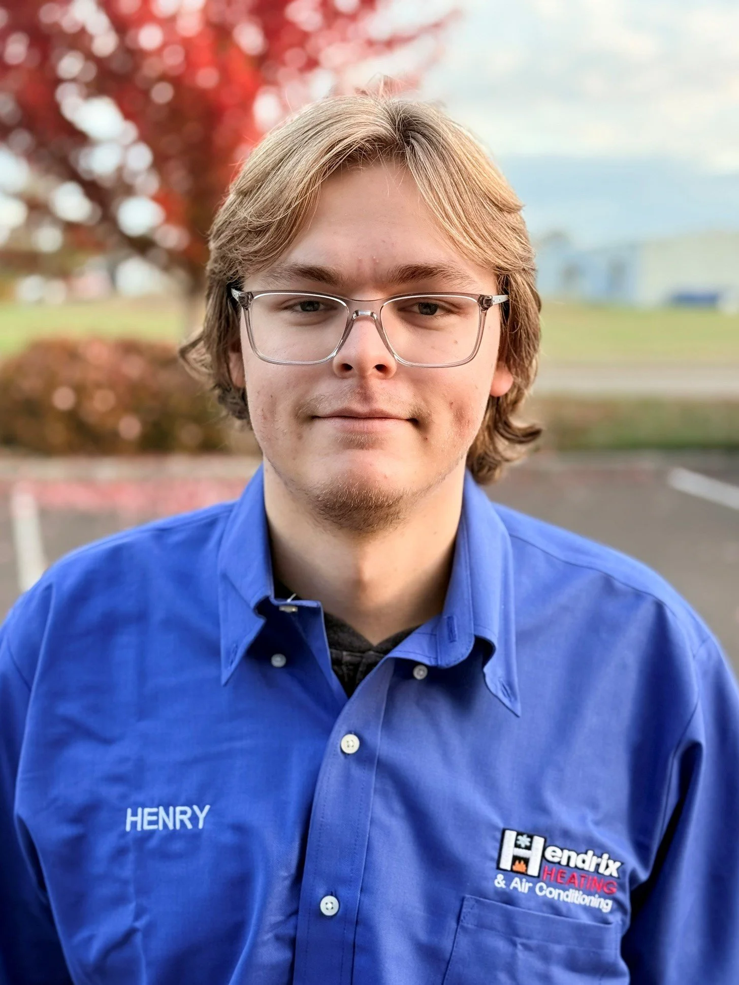 Person wearing glasses and a Hendrix Heating & Air Conditioning shirt and cap, standing outdoors.